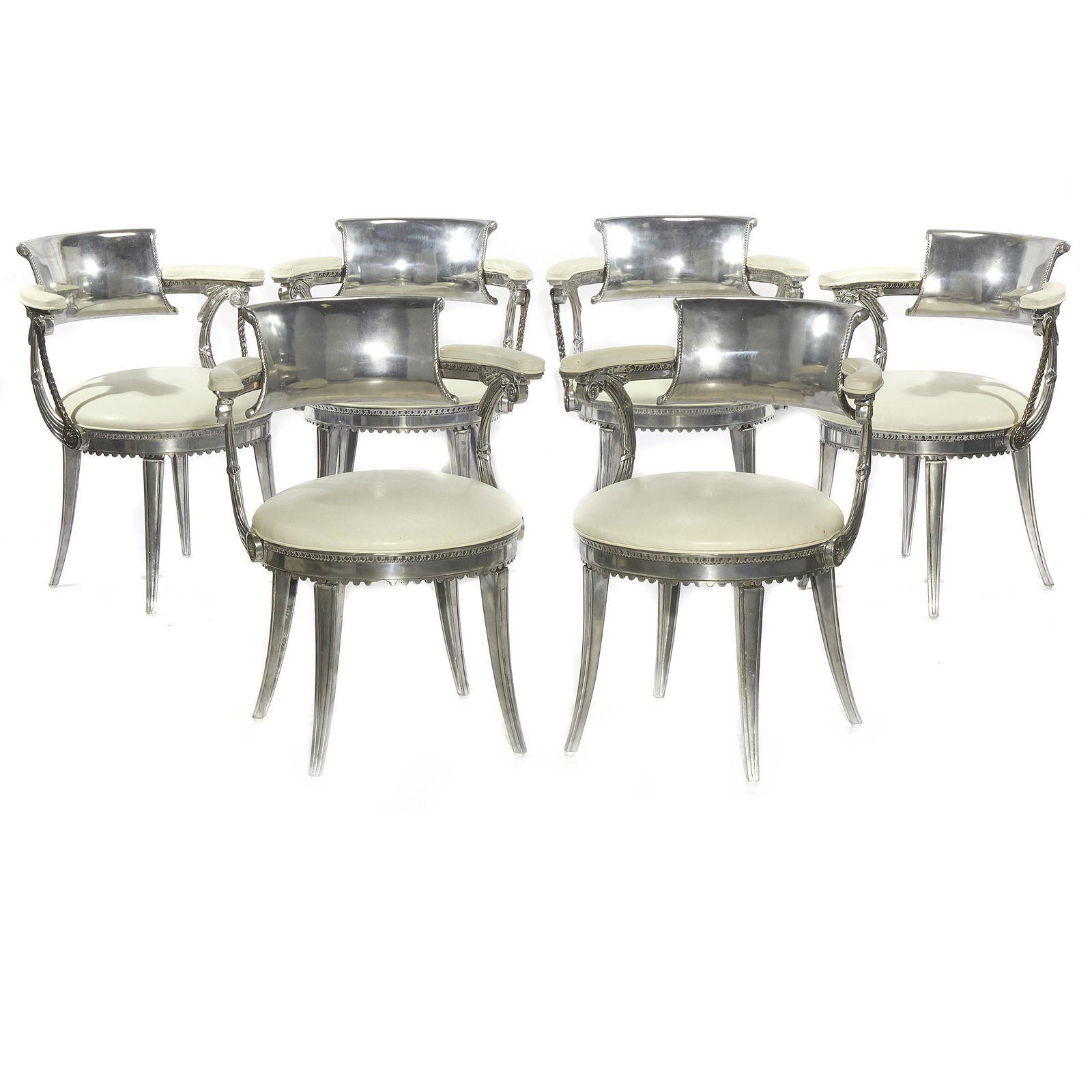 Six Art Deco Dorothy Draper Design Chairs: Of polished chrome and white leather cast with the curved back and arms on swept Pompeiian supports embossed on the crest back with a crown. . 29in. (74cm)h. 23in. (58cm) w. 18in. (46cm) d. Provenance