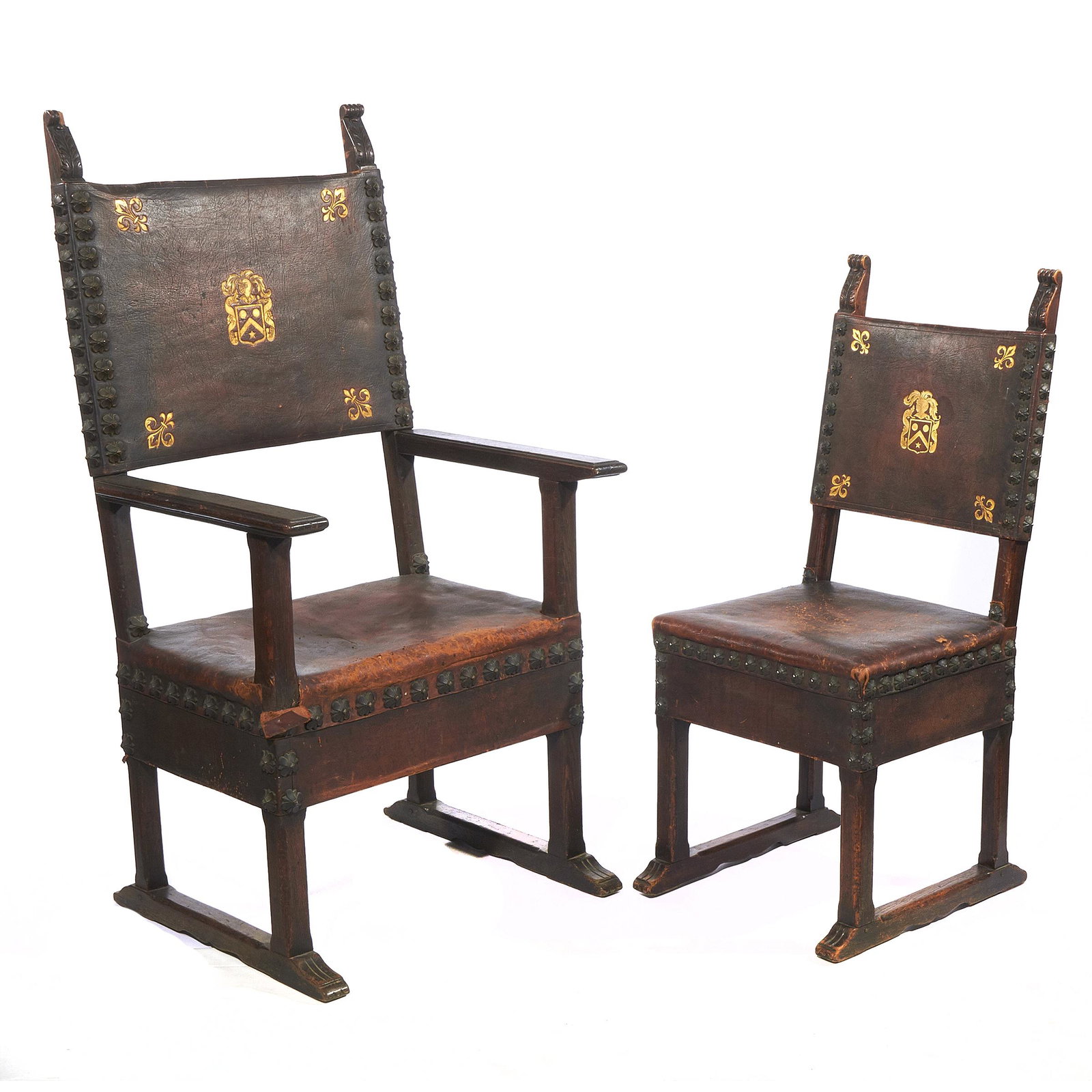 Set of Spanish Baroque Dining Chairs: A set of seven, including two arm chairs and five side chairs, each with acanthus carved finial over nail head trimmed leather back and seat embossed with gold herald. Armchairs 52in. h 22in. w. 18in.