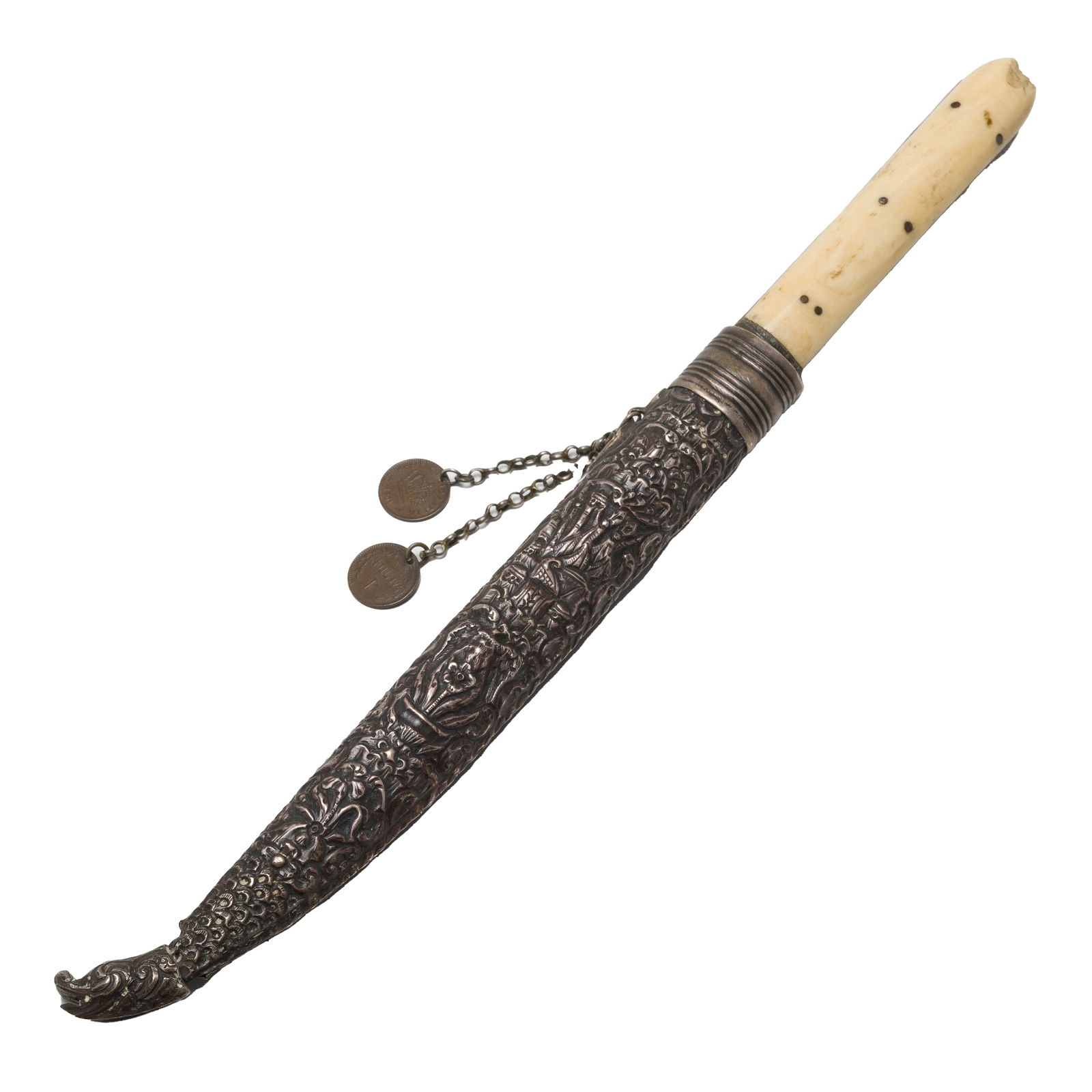 Cretan Knife, 1905: Cretan knife in a silver scabbard decorated with figural and nature scenes, with a dragon head tip and banded locket. Scabbard with a kerkeli suspending two chains with small coin-like ornaments attac