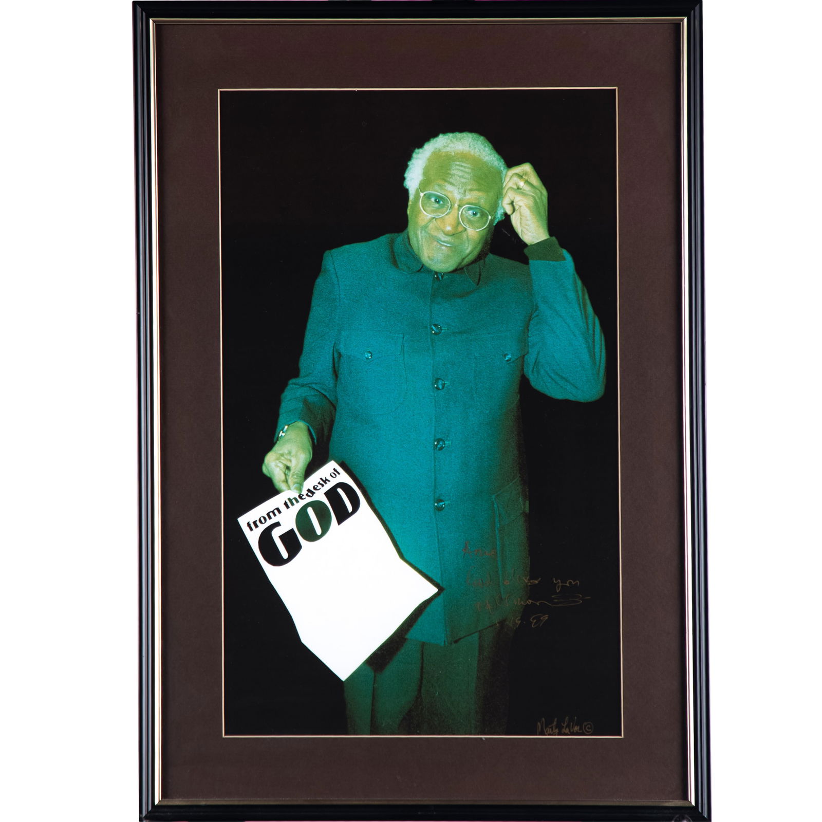 Marty La Vor (American, contemporary).: Marty La Vor (American, contemporary). From the desk of God, Desmond Tutu, 1989. Color photograph, signed by Desmond Tutu and signed and dated by the artist in the image, framed. 18 x 11in. (46 x