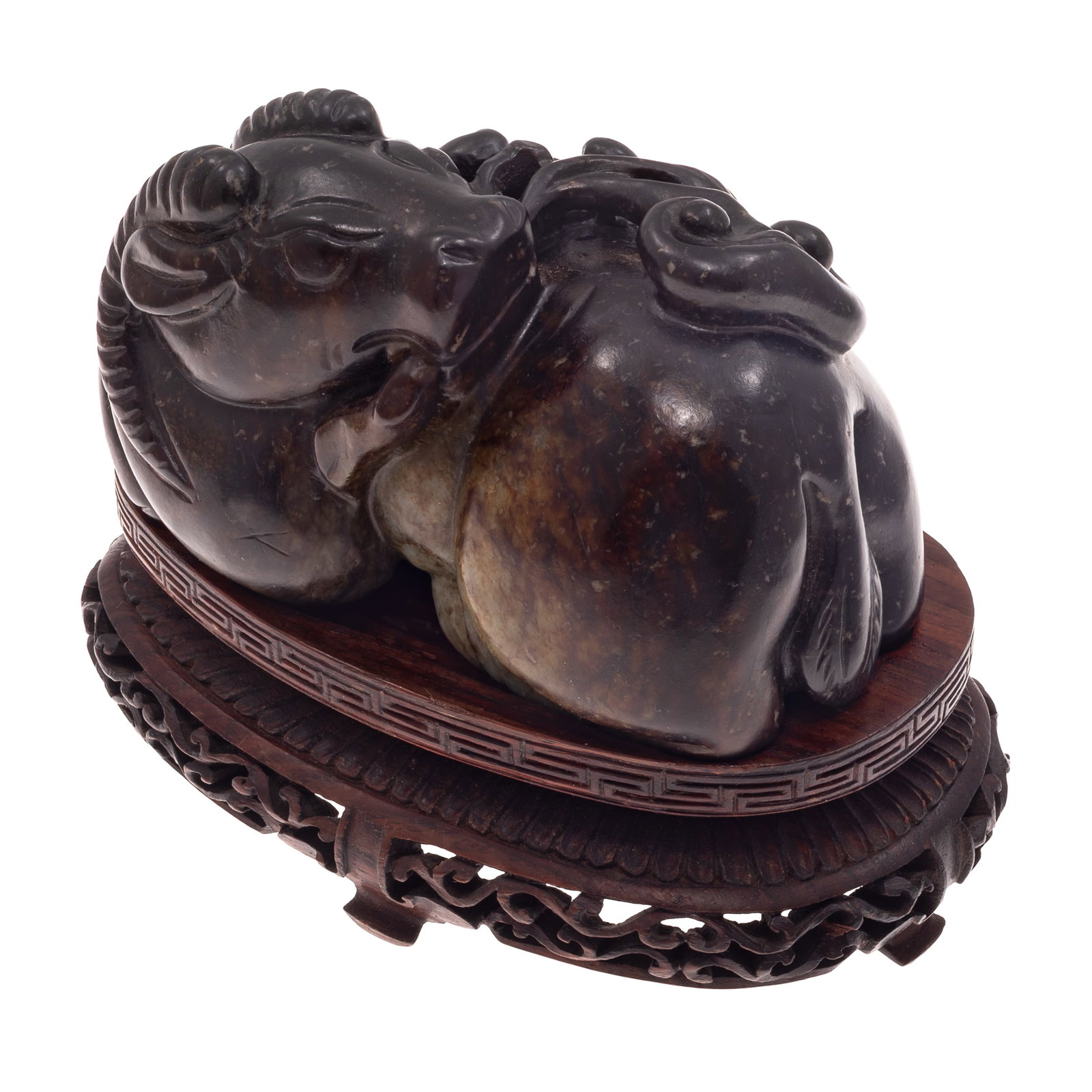 Chinese Jade Carving of a Horned Mythical Beast: Chinese Jade Carving of a Horned Mythical Beast Carved from a dark tone jade stone with natural russet and cream inclusions, the recumbent horned mystical beast shown grasping a leafy stem issuing a l