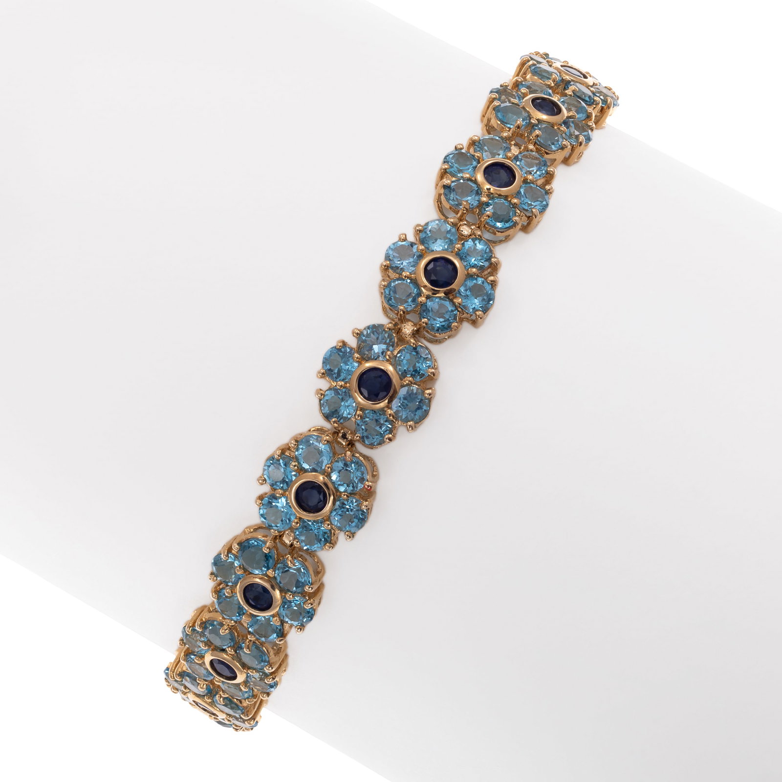Sapphire, Blue Topaz, 14k Yellow Gold Bracelet: Sapphire, Blue Topaz, 14k Yellow Gold Bracelet Designed as a series of twenty flowers, each centering one round-cut sapphire weighing a total of approximately 0.90 cttw., framed by six round-cut blue
