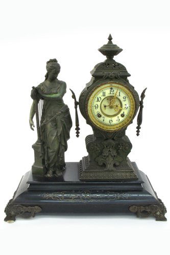 A VICTORIAN STATUE CLOCK, Ansonia Clock Co., "Musi: A VICTORIAN STATUE CLOCK, Ansonia Clock Co., "Music" model, c. 1894, with lady harp player and tower clock surmounting a rectangular black iron plinth with applied scroll bracket feet, the tower housi