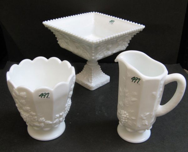 A GROUP OF THREE WESTMORELAND GLASS CO. MILK GLAS: A GROUP OF THREE WESTMORELAND GLASS CO. MILK GLASS TABLE ACCESSORIES, all in the vintage grape pattern, C. 1960, consisting of a square-form pedestal fruit bowl, 9-1/4 in. dia.; 8 in. ht.; around pede