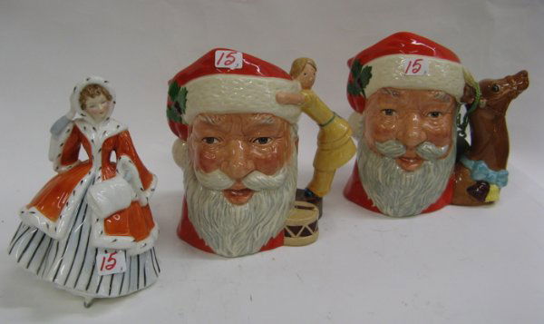 TWO ROYAL DOULTON CHARACTER MUGS AND A FIGURE. The: TWO ROYAL DOULTON CHARACTER MUGS AND A FIGURE. The mugs are of Santa Claus, D6668 and D6675, 7-1/2 in. hts.; together with a female figure, "Noelle", HN2179, 7-1/4 in. ht., 1957-67, orange coat with w
