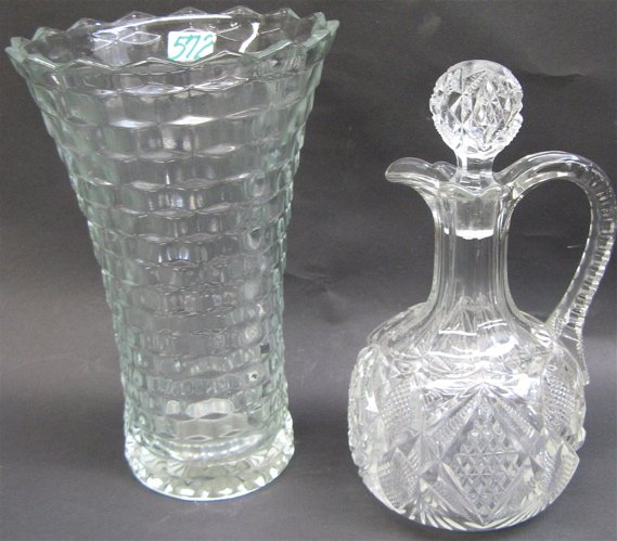 TWO PATTERN CLEAR GLASS TABLE ACCESSORIES. One i: TWO PATTERN CLEAR GLASS TABLE ACCESSORIES. One is a Fostoria tapered vase in the American pattern, 9-3/4 in. H.; the other a cordial decanter with original stopper in a diamond pattern, with side hand