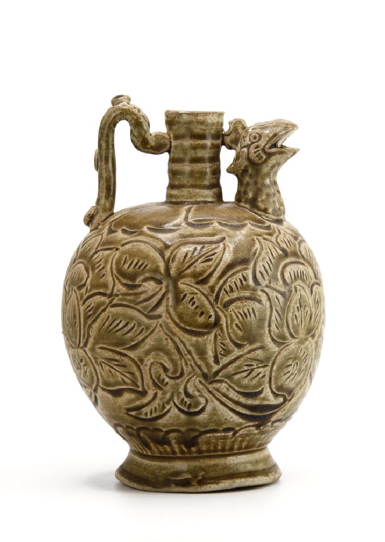 Yaozhou Carved "Chicken Head' Ewer: The globular body supported on a spreading foot, the shoulder moulded with lotus pedals, surmounted by a cylindrical neck with bow-string lines, set with a spout in a shape of chicken head and loop ha