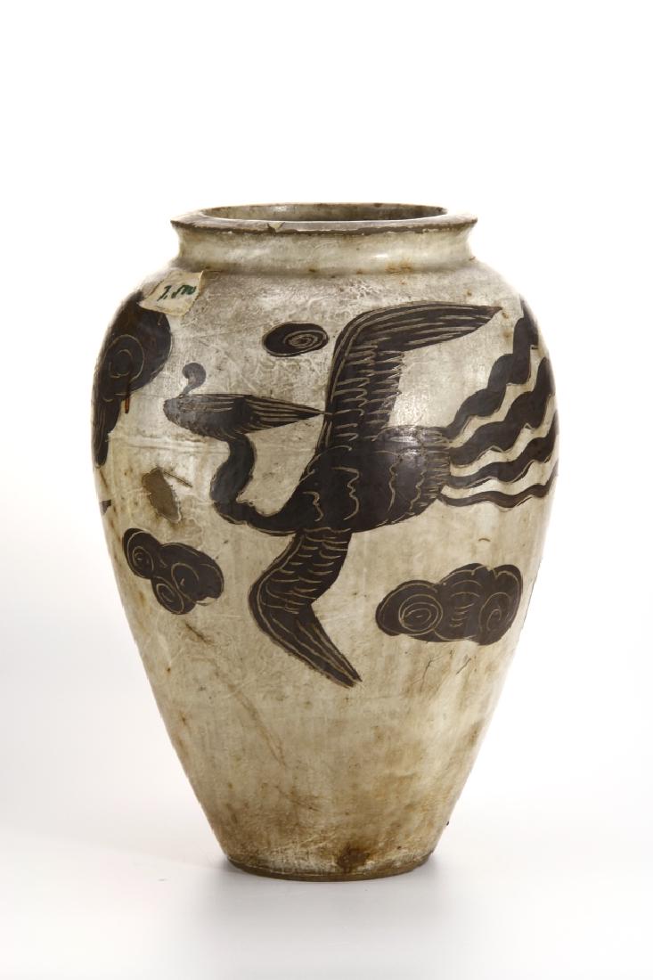 Cizhou 'Phoenix' Jar: Robustly potted, the ovoid body with narrow shoulders tapering to the foot, the body boldly painted with a band of flying phoenixes with outstretched wings amidst cloud scrolls. Height 12 in.