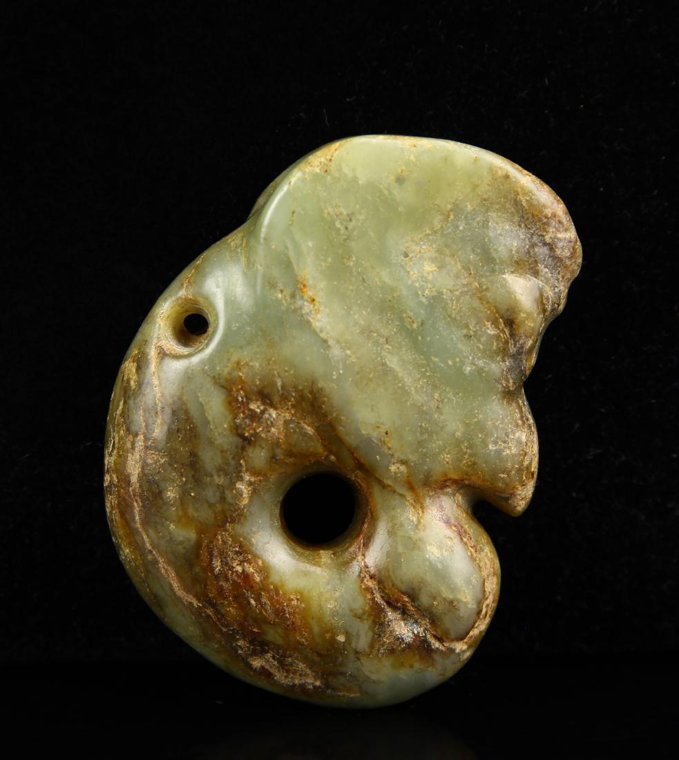 Hongshan Coiled Dragon: Yellow-green nephrite with brown altered patches. According to the Chinese legend Lord Jun, the supreme God of the East had a bird head with a sharp beak. Length 1 7/8 in. Private collection from Mrs.