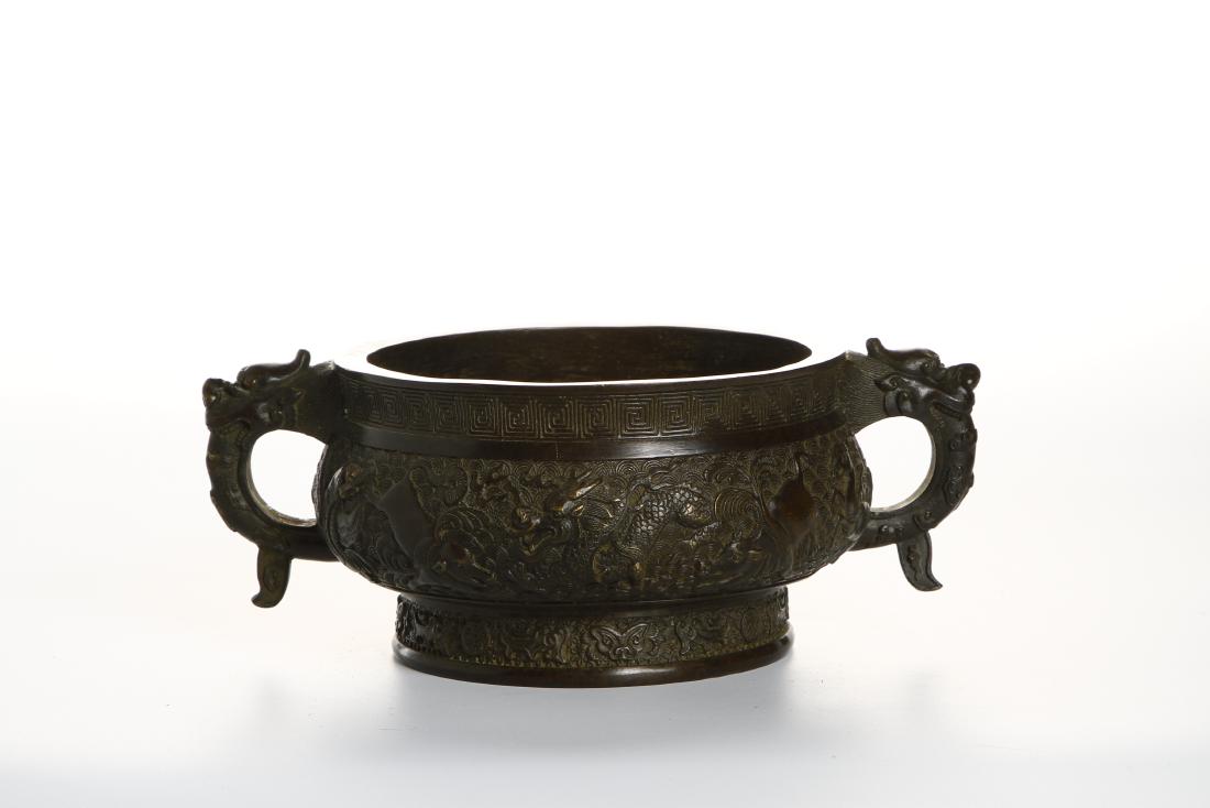Chinese Bronze Censer: Heavily cast with the bombé body rising from a slightly splayed foot to a flared mouth, flanked by a pair of dragon handles, crisply cast on each side with a scene of dragon amidst crashing waves, al