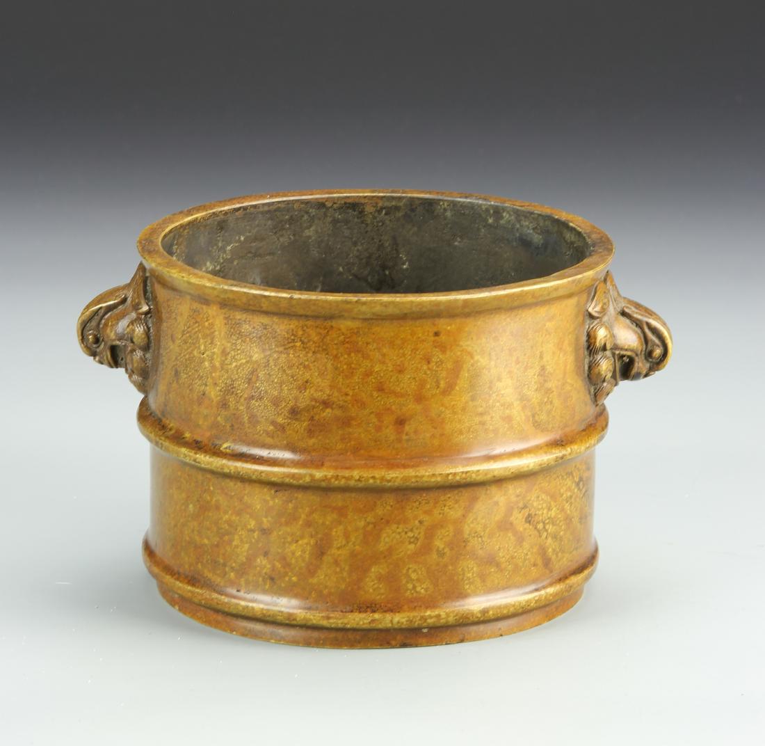 Chinese Bronze Censer: 19th C., in cylindrical form, with two mythical creature head ears, and ring detail around the body and base. Height 4 in., Width 7 in.