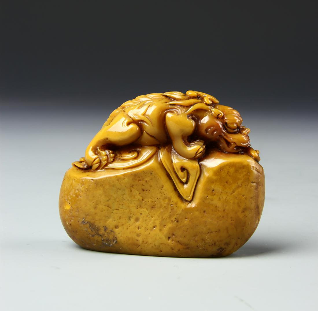 Chinese Soapstone Seal: Round body with organic edges, a carved foo lion on the top seated on all fours, deep orange hues throughout. Height 2 1/2 in.