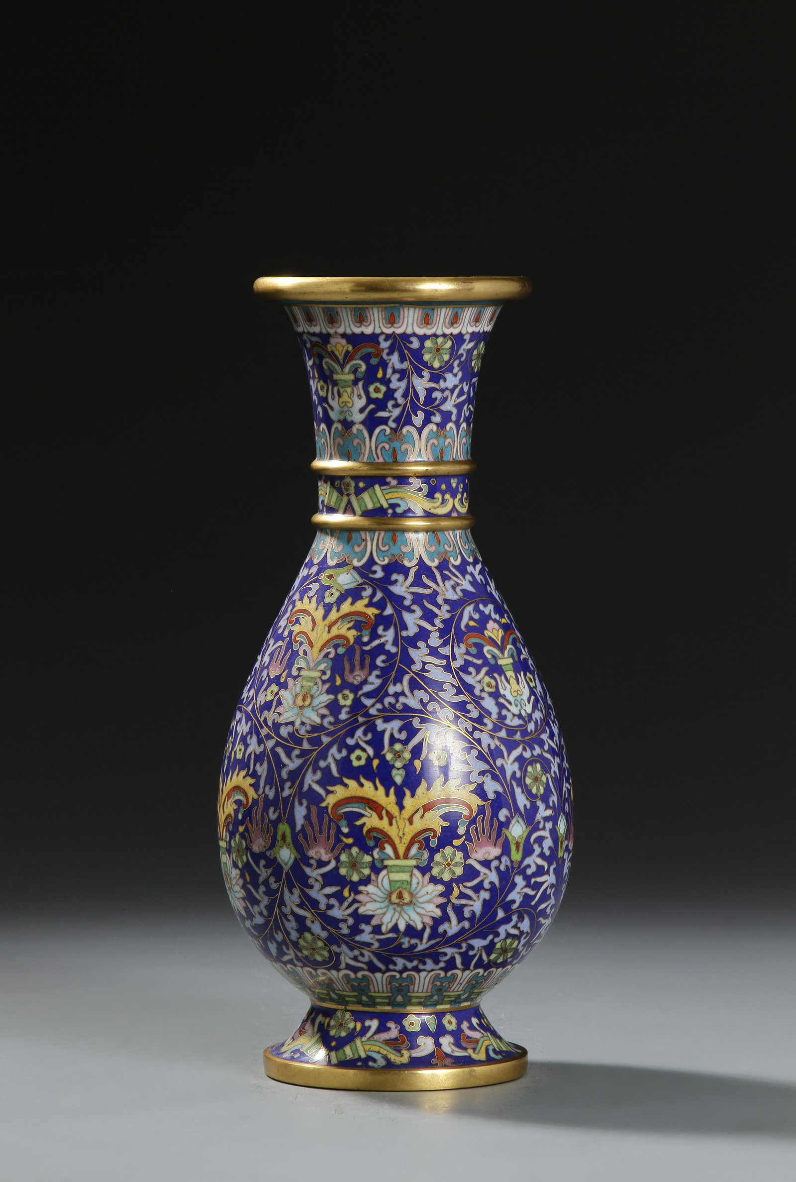 Chinese Cloisonne Enamel Vase: Pear-shaped body rising from a splayed foot to a slight everted rim, decorated in sections with floral blooms, surrounded by dense floral sprays, the rim, ribs and footring gilt, the base with turquoi