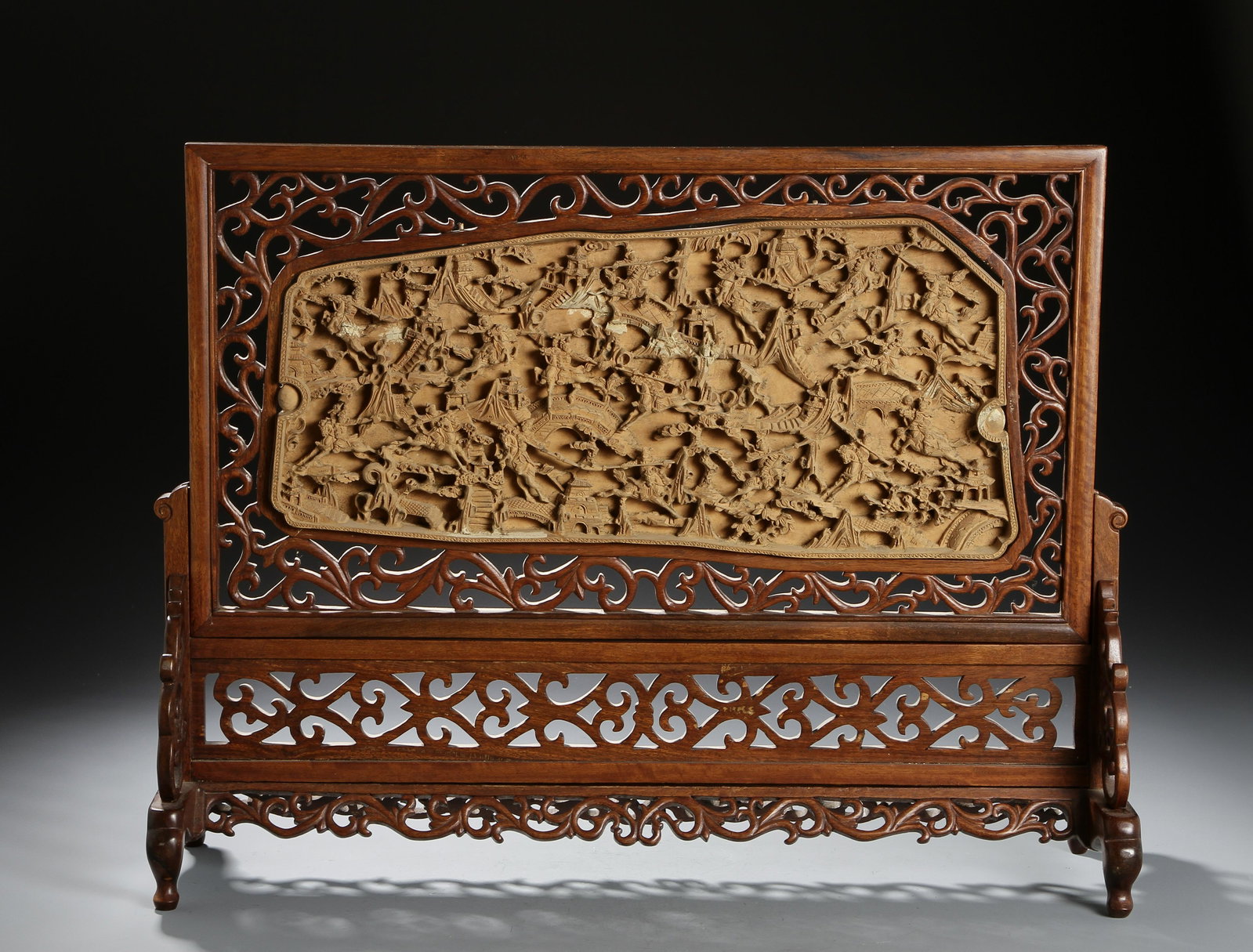 Chinese Carved Wood Table Screen: The horizontal rectangular panel finely carved to one side in relief with a war scene, the reserve plain, mounted in a carved and pierced wood frame and supported on a wood stand. Height 17 in., Width