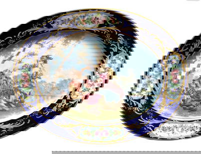 19th Century Sevres Hand-Painted Oval Porcelain Plate with Courting Scene: Elegant 19th century Sevres oval porcelain plate featuring a finely hand-painted Rococo scene of a courting couple seated beneath a tree beside a lake. The central image is framed by a deep cobalt blu