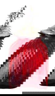 Ruby Red Glass Apothecary Jar with Fleur-de-Lis Metal Lid: Eye-catching and vibrant, this vintage ruby red apothecary jar features a beautifully swirled glass body in a rich cranberry tone. Topped with a metal lid crowned by a fleur-de-lis finial, the jar com