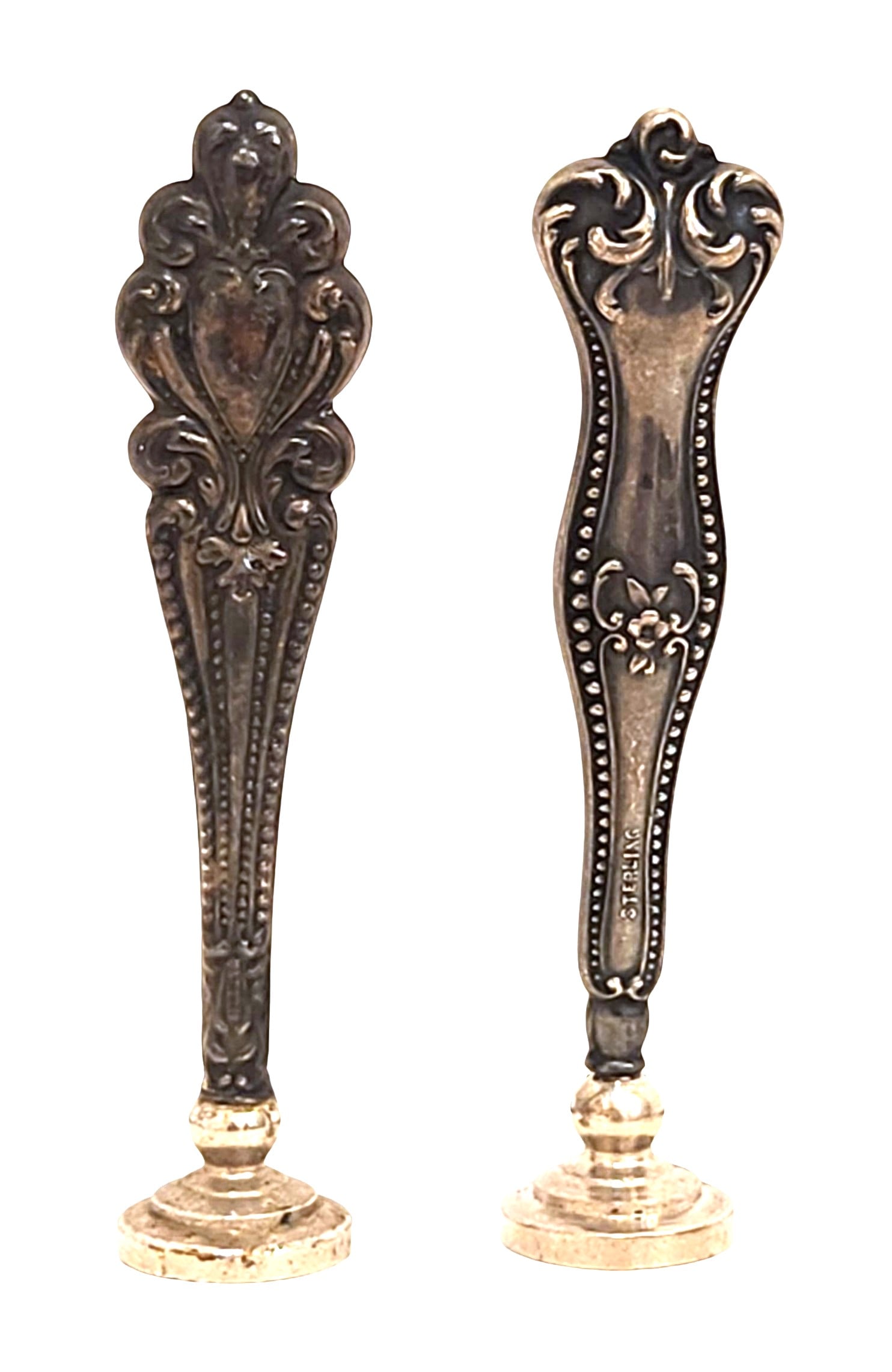 Pair of Sterling Silver Wax Seal Handles, Early 20th Century: A pair of sterling silver wax seal handles, each with ornate repoussé decoration. One handle with a beaded border and floral motif, marked STERLING. The bases are fitted for sealing, one engraved wit