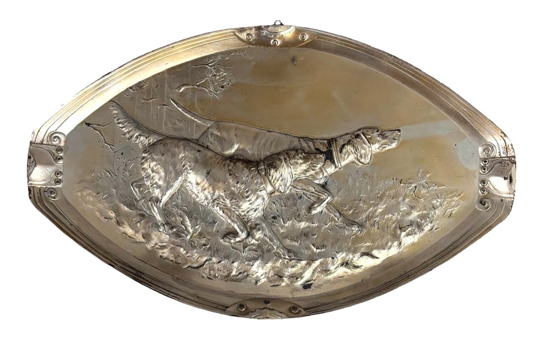 Antique Embossed Metal Hunting Dog Wall Plaque — Setter in Landscape Scene: A finely detailed antique embossed metal wall plaque featuring a hunting dog—likely a setter or pointer—captured in mid–tracking stance. The raised relief showcases impressive craftsmanship, wit