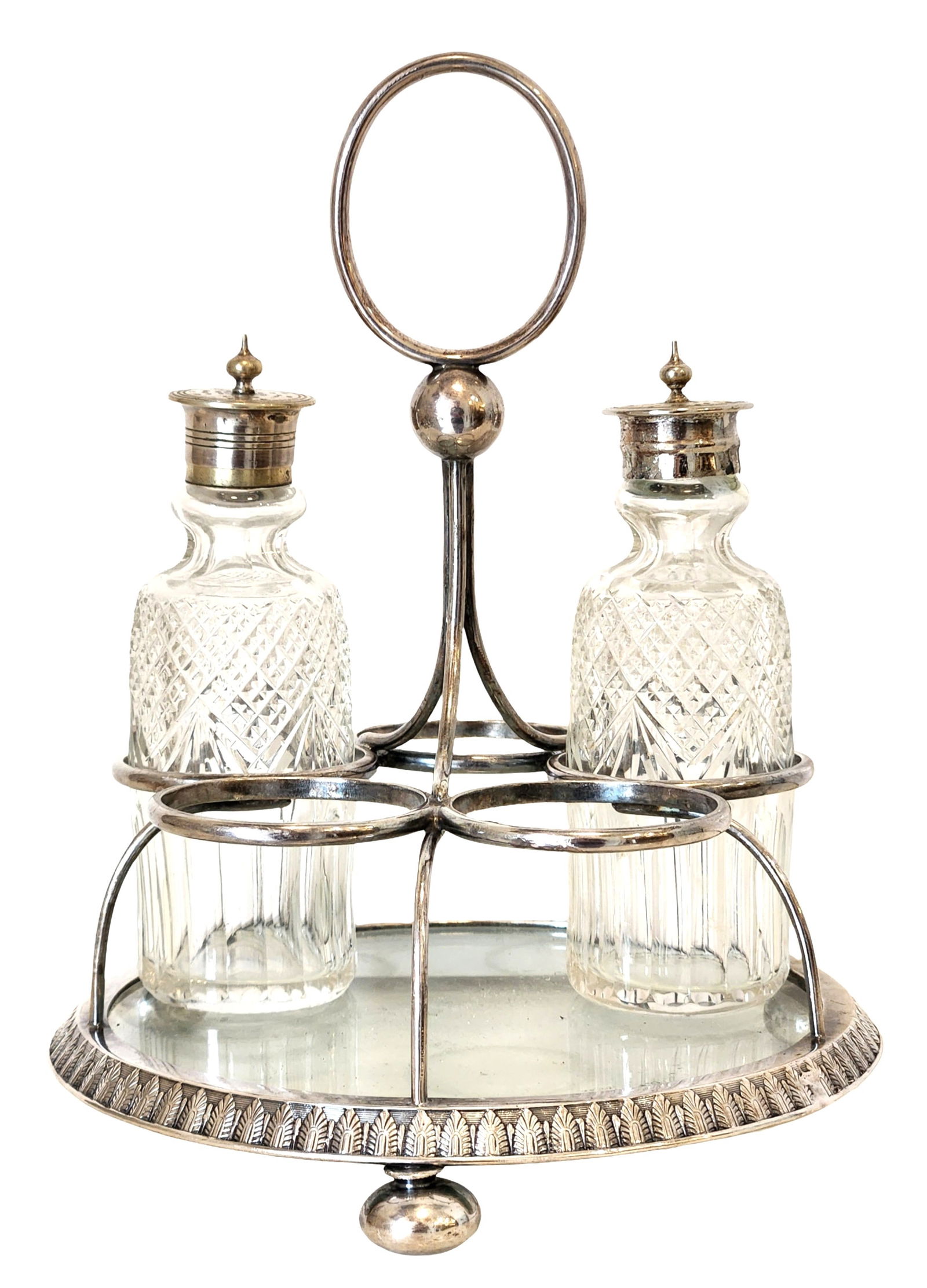 Vintage Silver-Tone Cruet Set with Cut Glass Bottles on Stand: Vintage cruet set comprising four cut glass bottles housed in a silver-tone metal stand with central carrying handle. The stand features a circular tray base with decorative border and four holders de