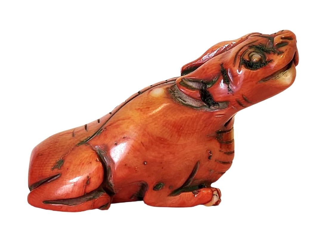 Antique Carved Red Coral Figure of a Tiger, Mid-20th Century: A finely carved red coral figure of a tiger, shown seated with head raised and mouth open in a dynamic pose. The carving features incised details of stripes and facial features, highlighting both arti