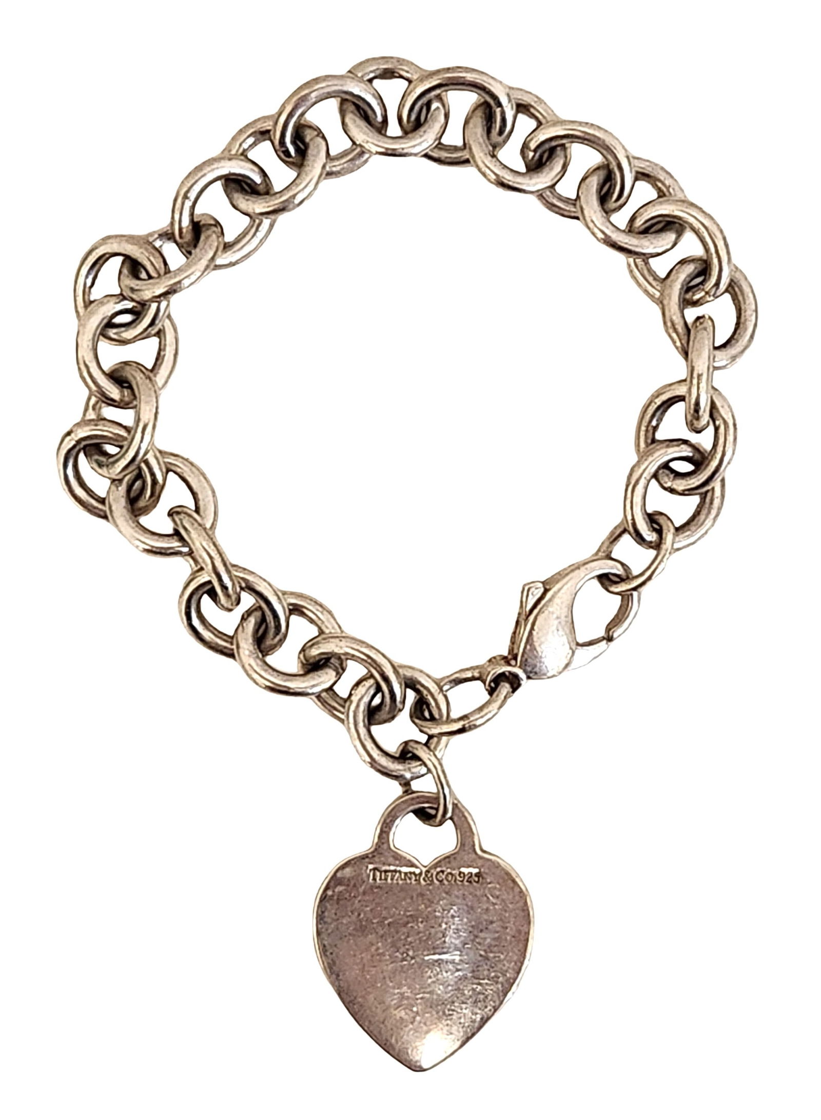 Tiffany & Co. Sterling Silver Charm Bracelet with Heart Tag, Engraved “Sheryl: Sterling silver charm bracelet by Tiffany & Co., featuring a classic round-link chain with a heart-shaped tag charm. The heart tag is stamped “TIFFANY & CO.” on one side and engraved “Sheryl