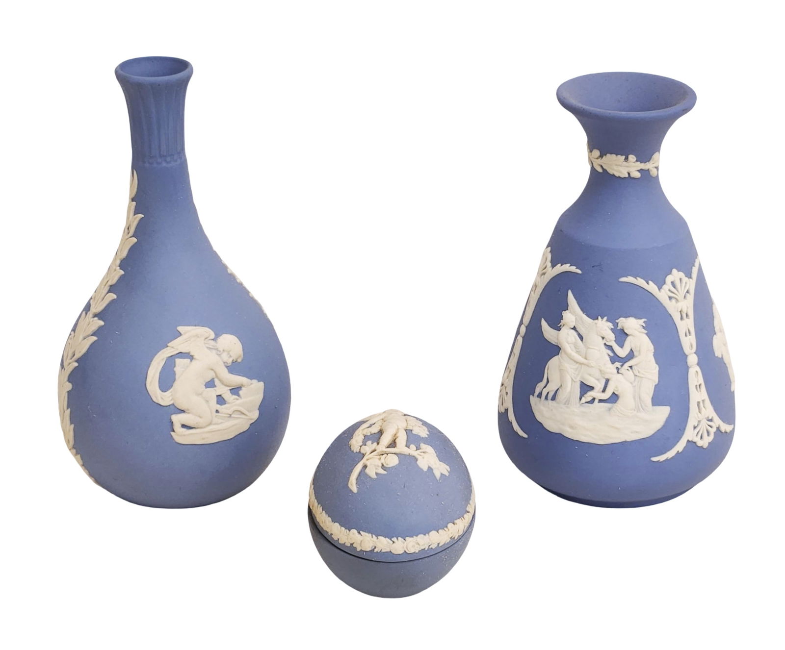 Group of Three Wedgwood Blue Jasperware Pieces, 20th C.: A group of three Wedgwood blue jasperware items with white classical reliefs, including: One slender bottle-form vase. One baluster-form vase. One round covered box All marked on the underside Wedgwoo