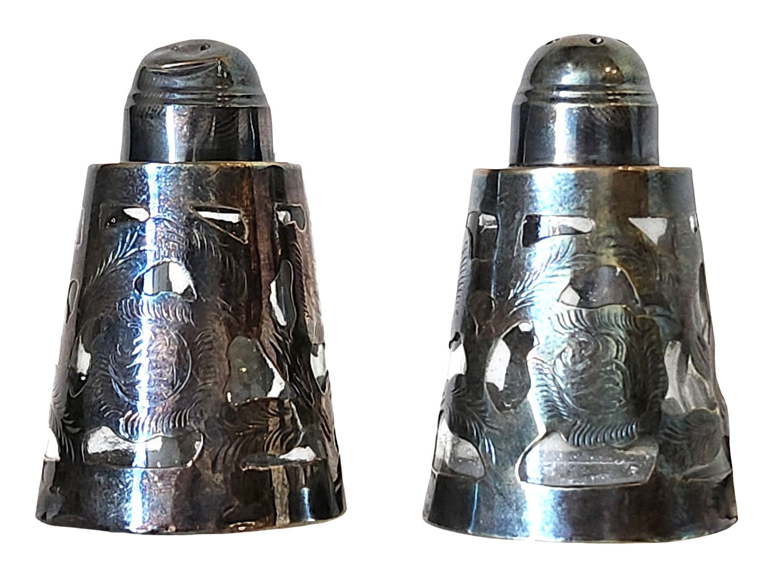 Pair of Sterling Silver Salt and Pepper Shakers, Early 20th Century: A matched pair of sterling silver salt and pepper shakers, each of tapering cylindrical form with pierced domed tops. The bodies are decorated with repoussé foliate and cartouche motifs, consistent w