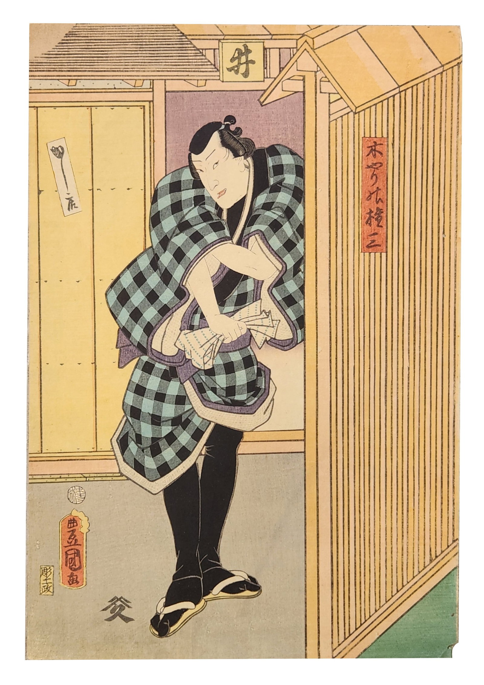 Japanese Ukiyo-e Woodblock Print of Kabuki Actor with Fan, Utagawa Kunisada School, Edo Period: Japanese ukiyo-e color woodblock print depicting a kabuki actor standing at the entrance of a traditional wooden building. The figure wears a checkered kimono and holds a folded fan, posed in a charac