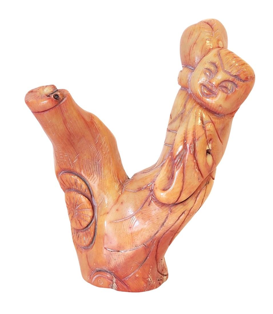 Antique Carved Red Coral Figure of a Child, Mid-20th Century: A carved Mediterranean red coral figure depicting a smiling child with stylized robes, worked from a natural coral branch. The piece highlights the organic striations, inclusions, and warm red-orange