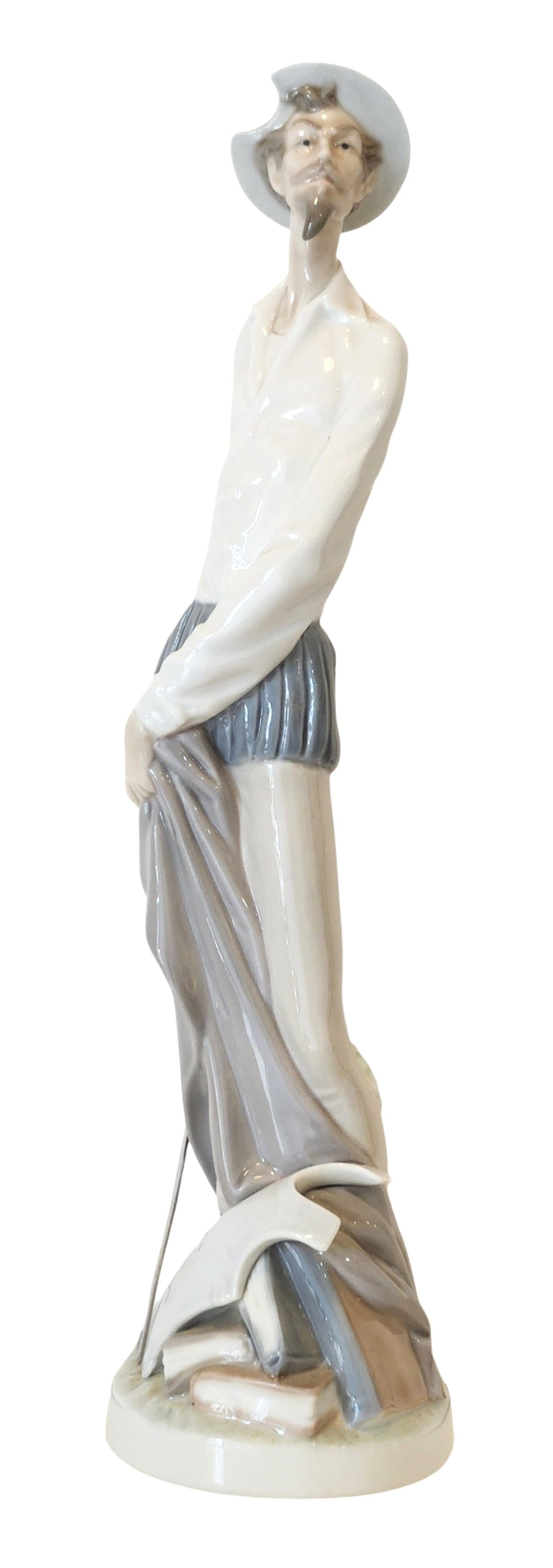 Lladro Porcelain Figurine – Don Quixote with Sword, Daisa, Hand Made in Spain: A classic Lladro porcelain figurine depicting the iconic literary character Don Quixote, portrayed in a slender, elongated form with a thoughtful upward gaze. He is shown holding a sword, dressed in t