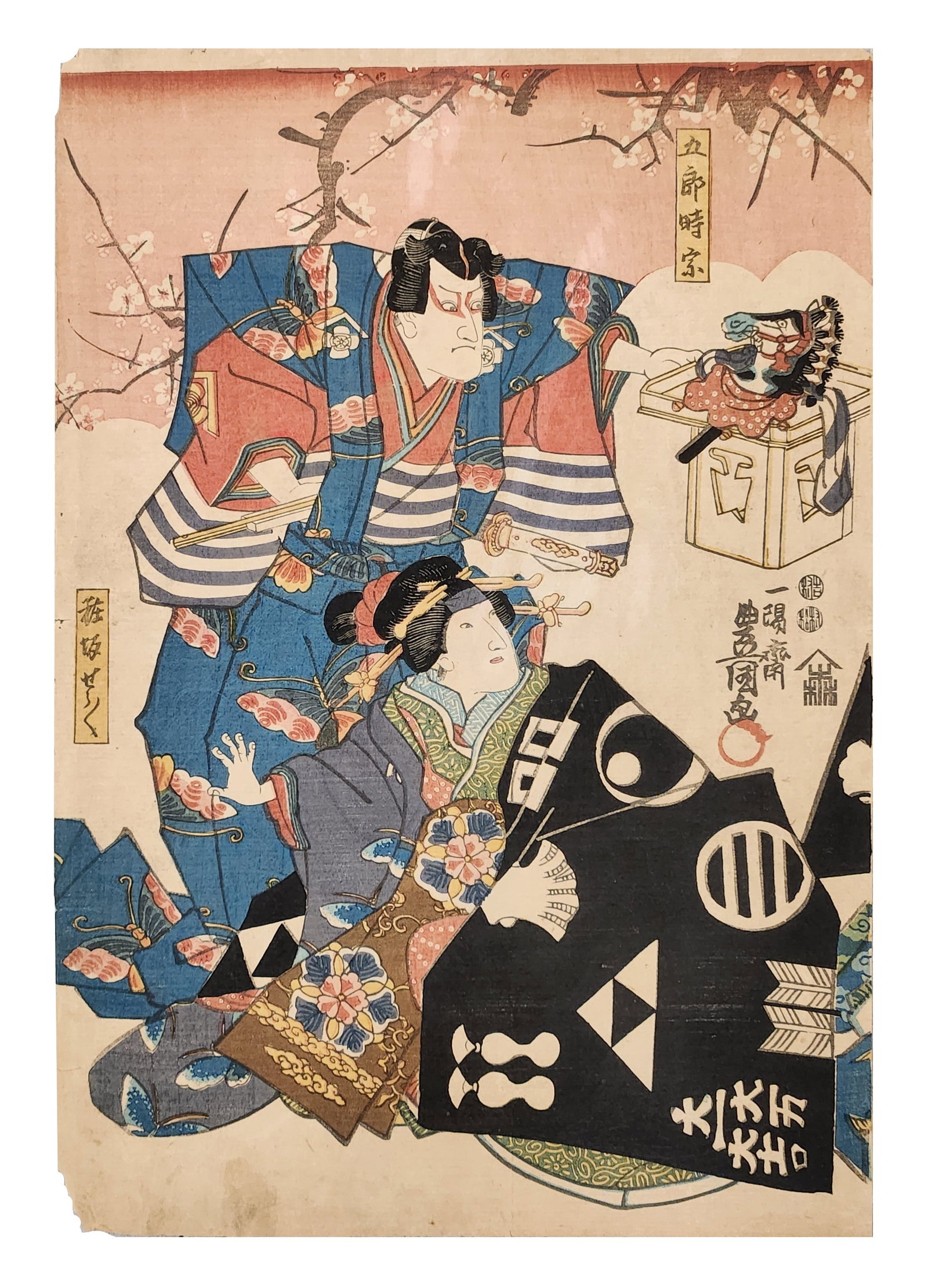 Antique Japanese Ukiyo-e Woodblock Print – Kabuki Scene – Edo Period (c. 1800s): Striking antique Japanese ukiyo-e woodblock print depicting a dramatic kabuki theatre scene. The composition features a boldly dressed male actor in a vivid blue robe confronting a seated female figur