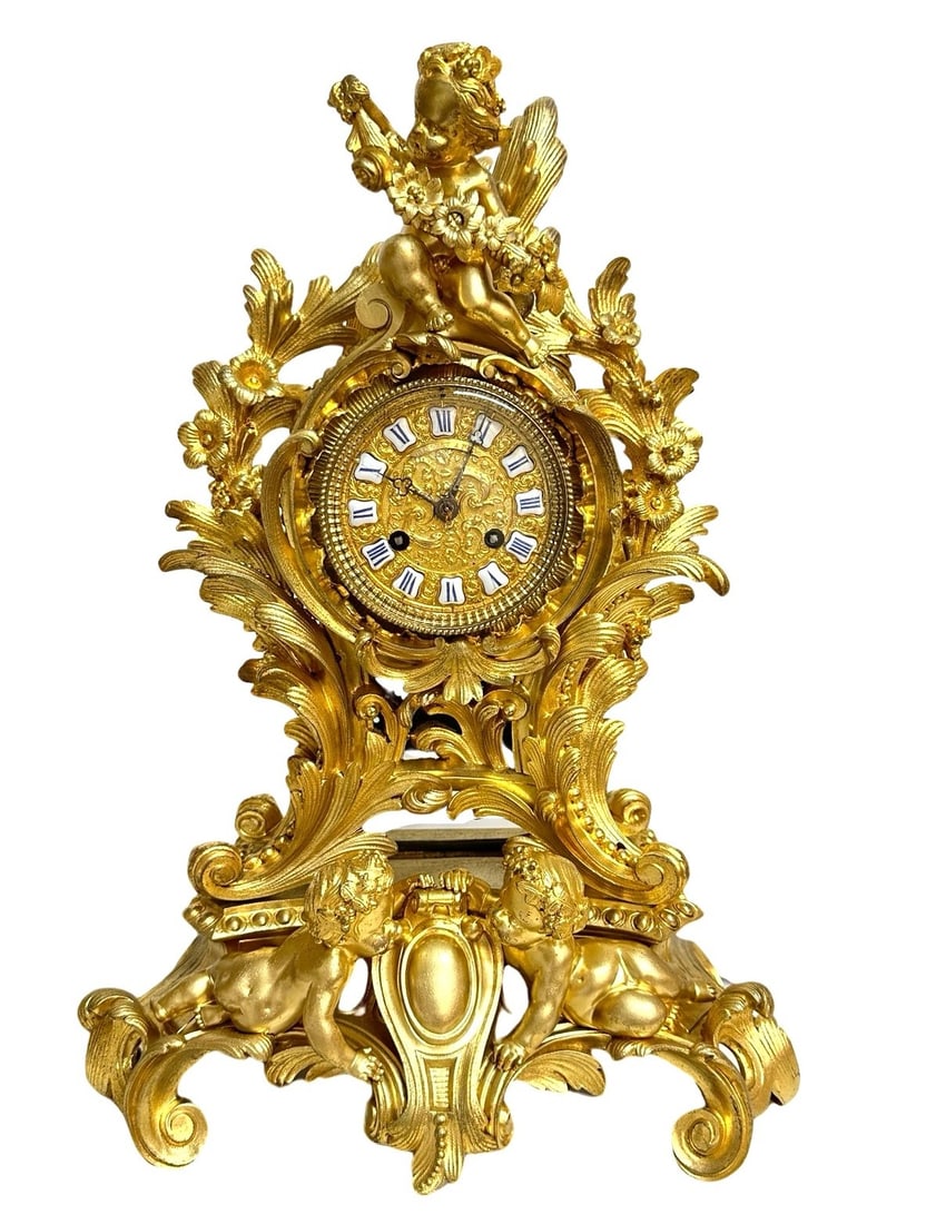 French 19th Century Louis XV Style Bronze Dore Matel Clock by Ringuet A Paris: Antique gilt bronze clock by Ringuet A Paris featuring a movement mounted in a foliage laden housing topped with a flower crowned putto hanging a garland Housing stands on a four footed base adorned w