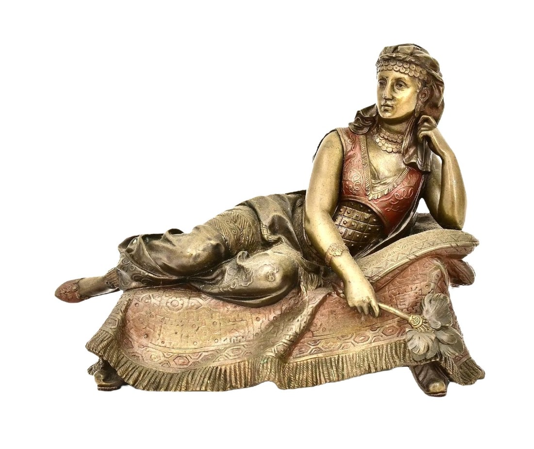 Large 19th-Century French Orientalist Patinated & Polychromed Bronze Sculpture of a Reclining Woman: Elegant French patinated and polychromed bronze sculpture depicting a reclining woman in richly detailed Orientalist attire. She rests gracefully on an elaborately textured cushion, her pose relaxed y