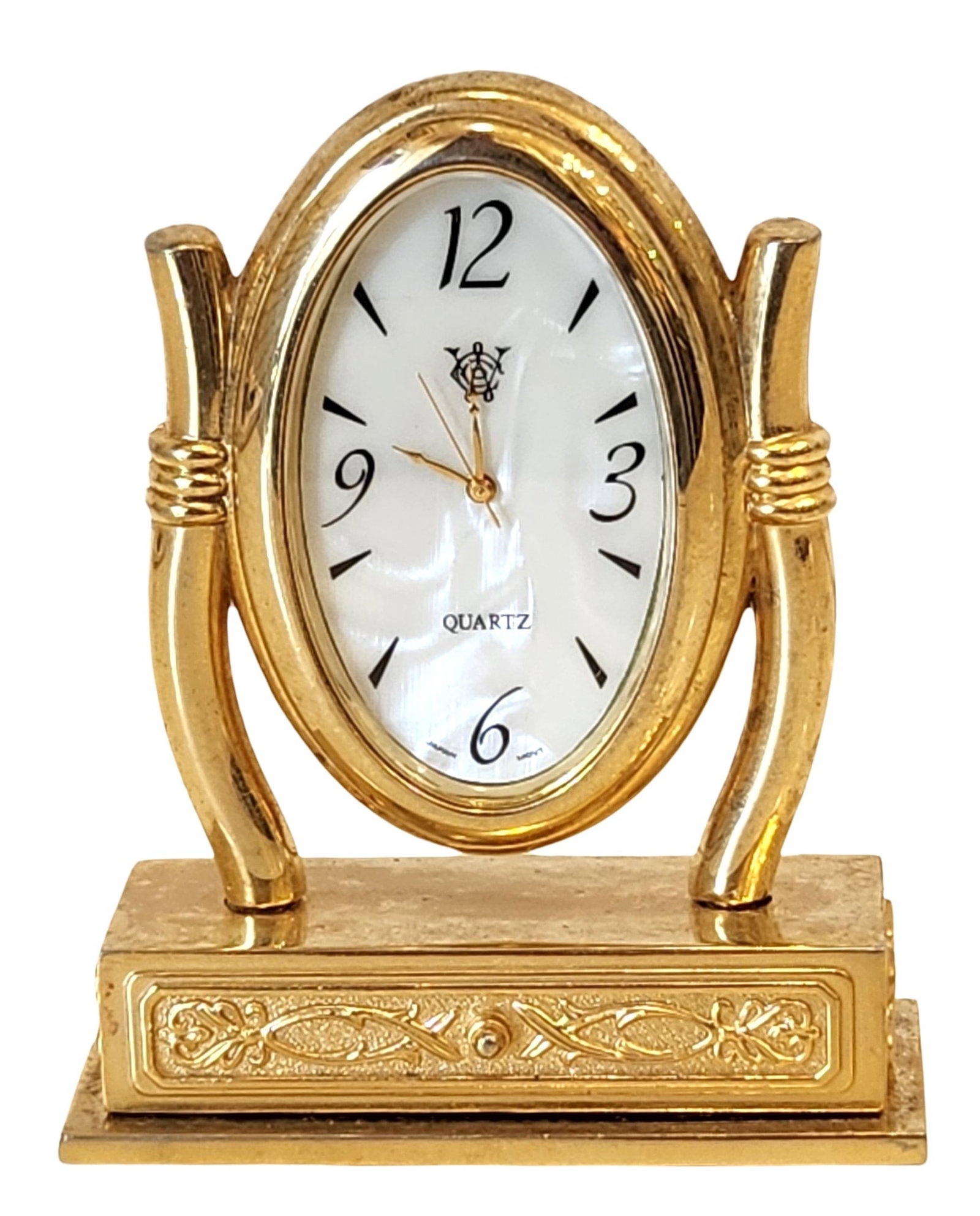 Brass Quartz Desk Clock with Oval Dial and Decorative Base: Decorative brass desk clock featuring an oval white dial with Arabic numerals, gold-tone hands, and a quartz movement. The clock is supported by a pair of curved brass uprights mounted on a rectangula