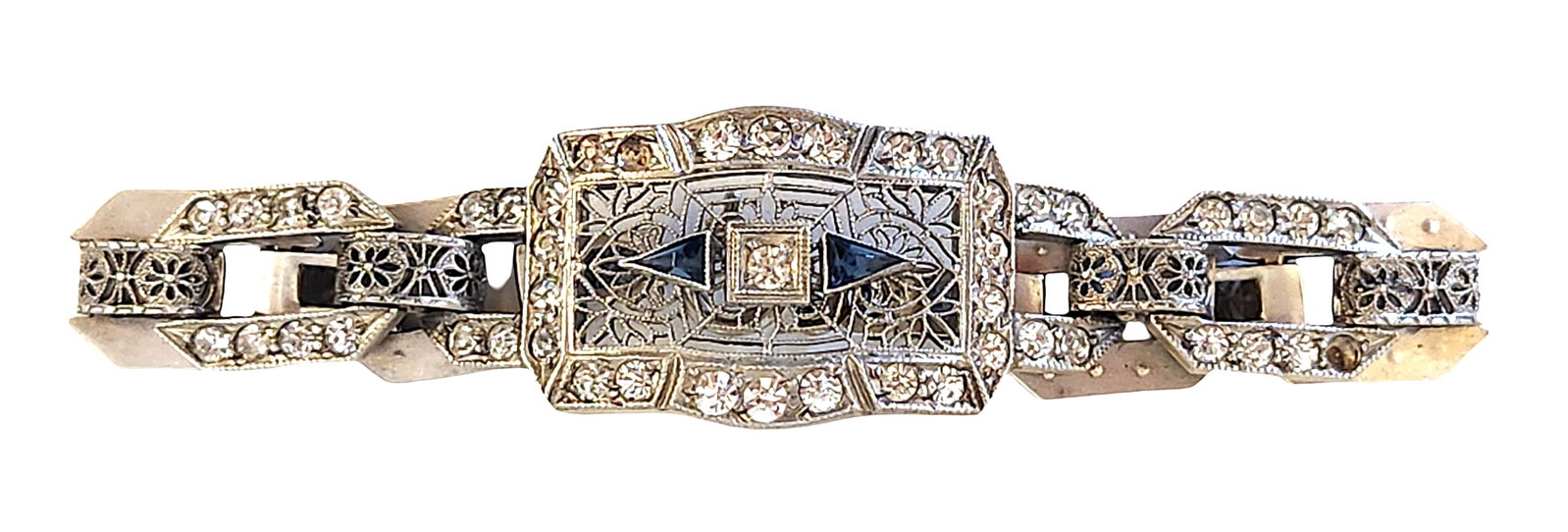 Art Deco Sterling Silver Filigree Bracelet with Blue Accents and Paste Stones: Art Deco style sterling silver bracelet featuring an openwork filigree design accented with clear paste stones and dark blue triangular accents. The central plaque is framed by geometric motifs and se