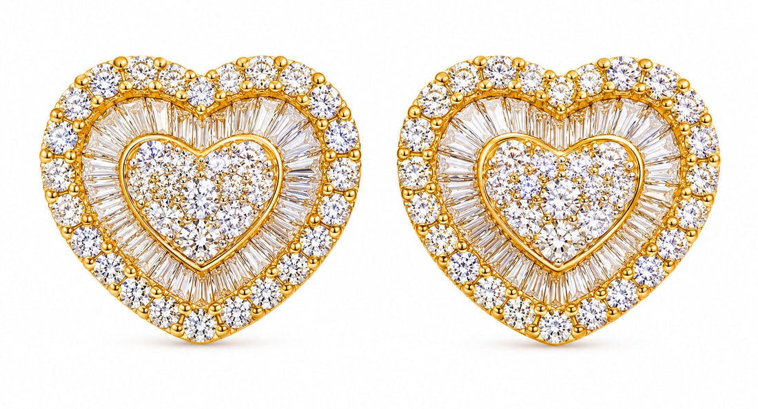 Pair of 14K Yellow Gold Natural Diamond Heart Stud Earrings, Approx. 0.76 CTW: Romantic and elegant pair of 14K yellow gold natural diamond heart-shaped stud earrings featuring a brilliant combination of round and baguette-cut diamonds. Each earring is designed with a raised dia