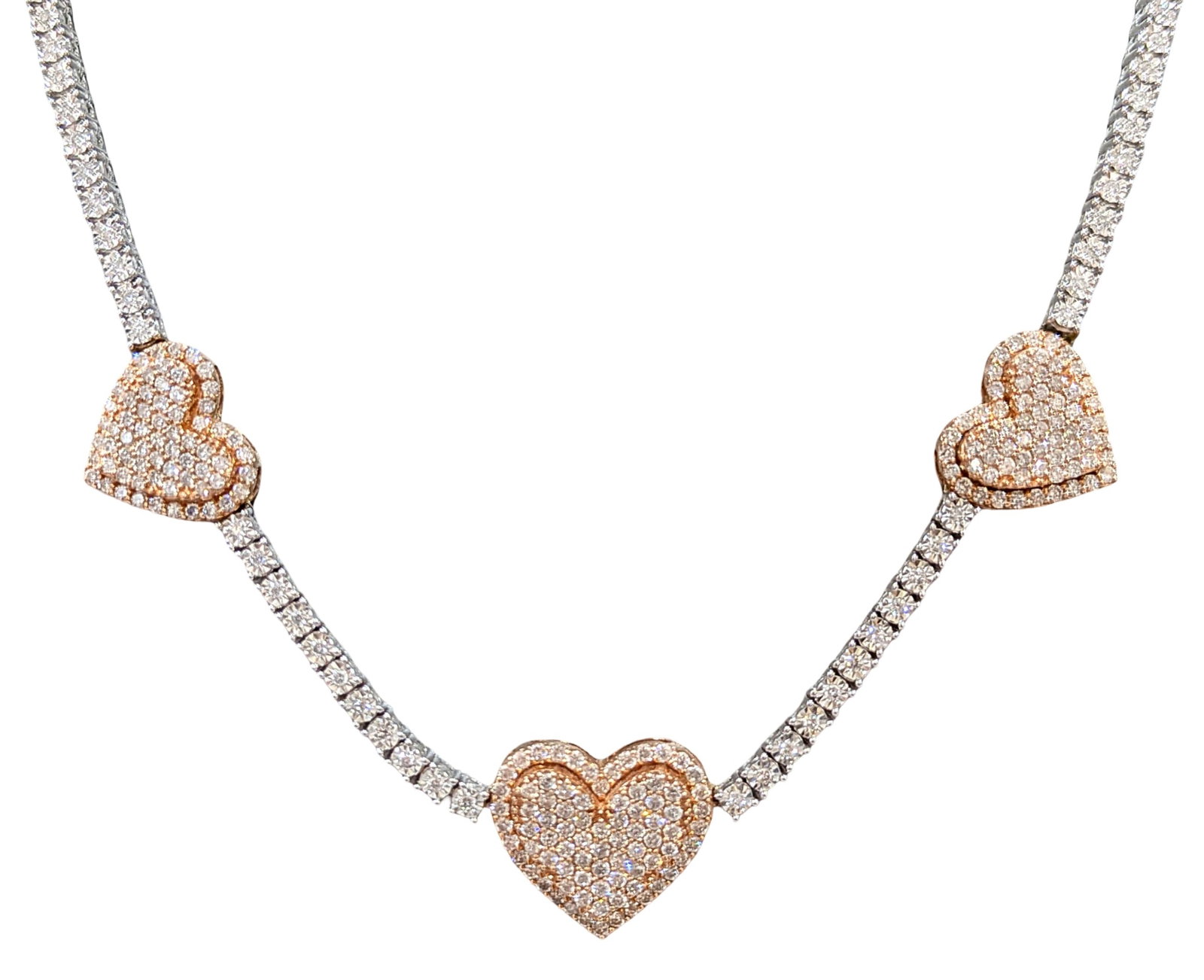 10KT White Gold Diamond Tennis Necklace with Rose Gold Heart Stations, 3.75 CTW: Elegant and eye-catching diamond tennis necklace crafted in solid 10KT white gold featuring three stunning rose gold heart stations fully iced with shimmering round diamonds. The necklace combines a c