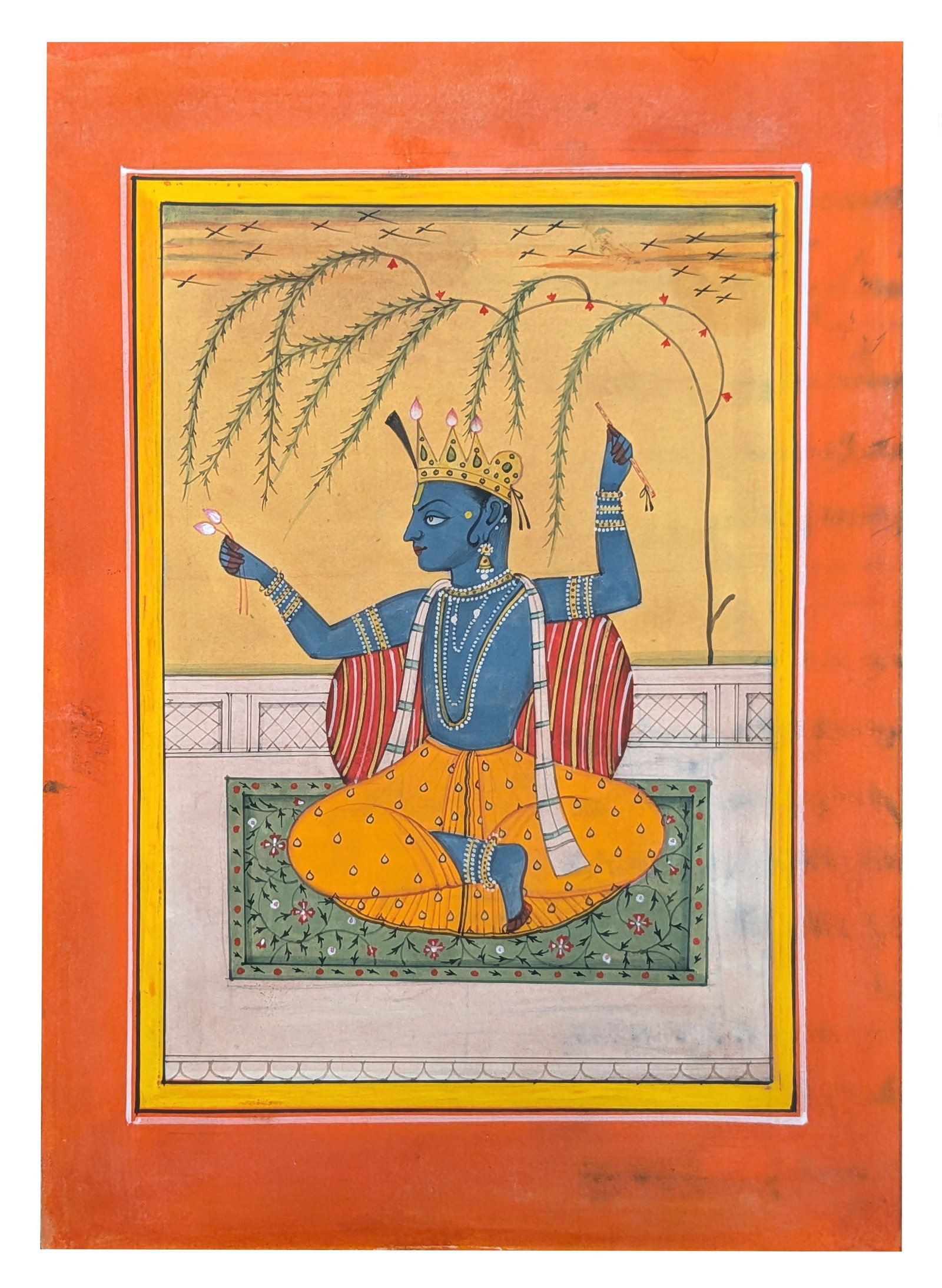 Indian Miniature Painting of Krishna Holding Lotus Blossoms: Indian miniature painting depicting the blue skinned deity Krishna seated cross legged upon a floral carpet before a striped bolster cushion beneath the graceful branches of a flowering tree. Wearing 