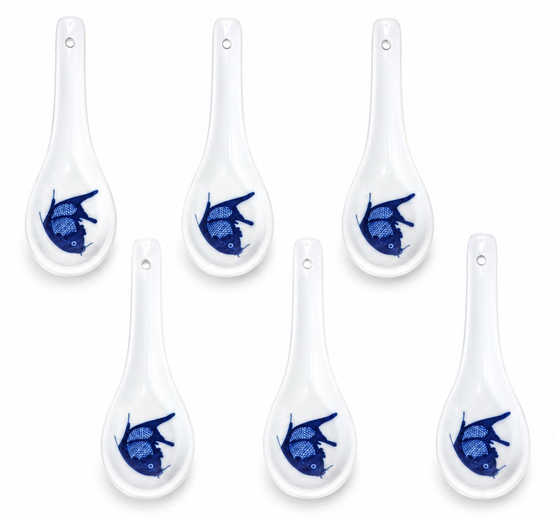 Set of Six Japanese Blue and White Porcelain Fish Motif Soup Spoons: A charming set of six Japanese porcelain soup spoons, each decorated in underglaze cobalt blue with a stylized fish motif against a white glazed ground. The spoons feature elongated handles with hangi