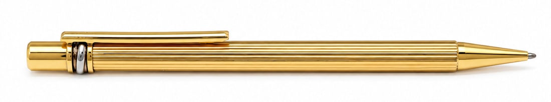 Must de Cartier Gold Plated Ballpoint Pen: Elegant Must de Cartier ballpoint pen featuring a gold plated finish with the iconic vertically fluted design. The pen is engraved " must de Cartier " near the tip and bears the Cartier double C logo 