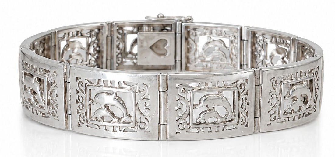 Sterling Silver Dolphin Link Bracelet: Crafted in sterling silver, this articulated link bracelet features openwork rectangular panels, each decorated with a pair of dolphins framed by ornate scrolling details. The bracelet is completed wi