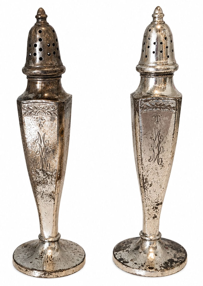 Pair of Sterling Silver Weighted Salt and Pepper Shakers: Elegant pair of sterling silver weighted salt and pepper shakers featuring a classic tapered form with finely engraved floral and foliate decoration. Each shaker is adorned with a monogrammed cartouch