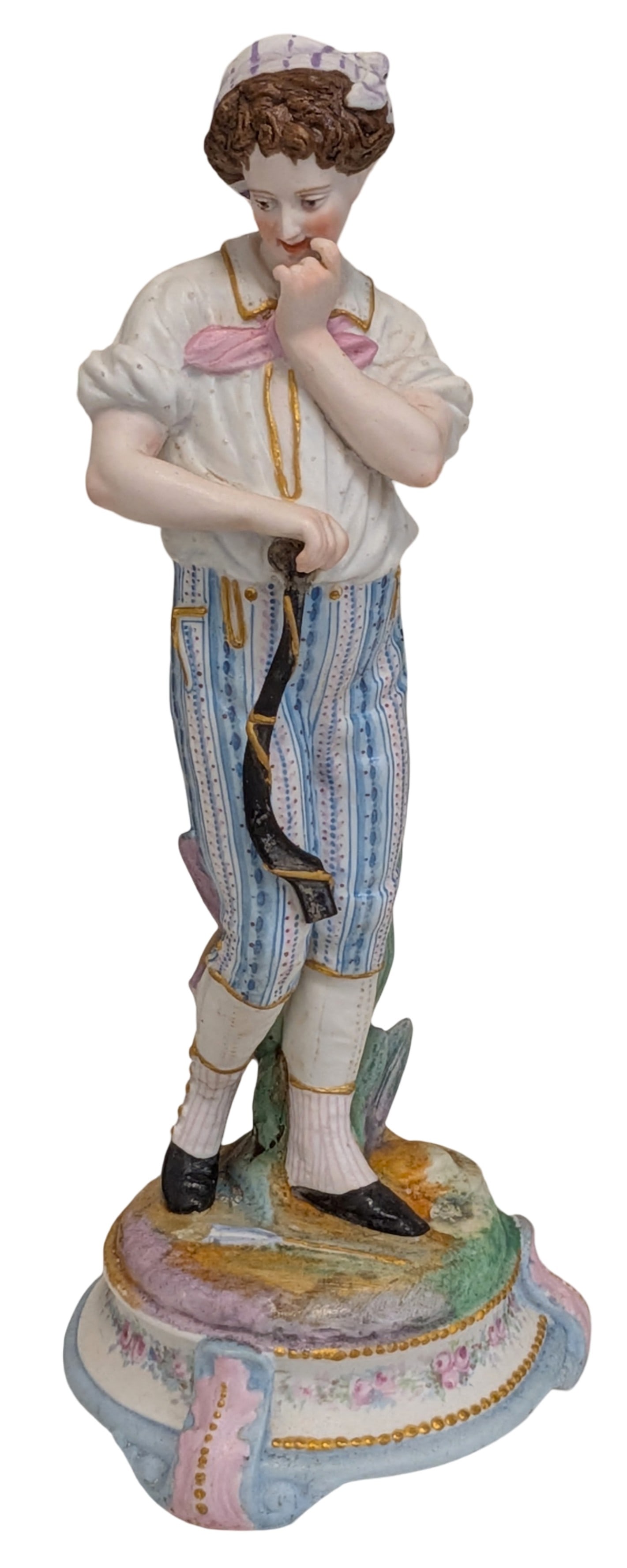 European Porcelain Figure of a Young Boy with Walking Stick, Late 19th/Early 20th Century: Finely modeled European porcelain figure depicting a young boy standing in a contemplative pose, holding a rustic walking stick with one hand while resting the other thoughtfully against his chin. He 