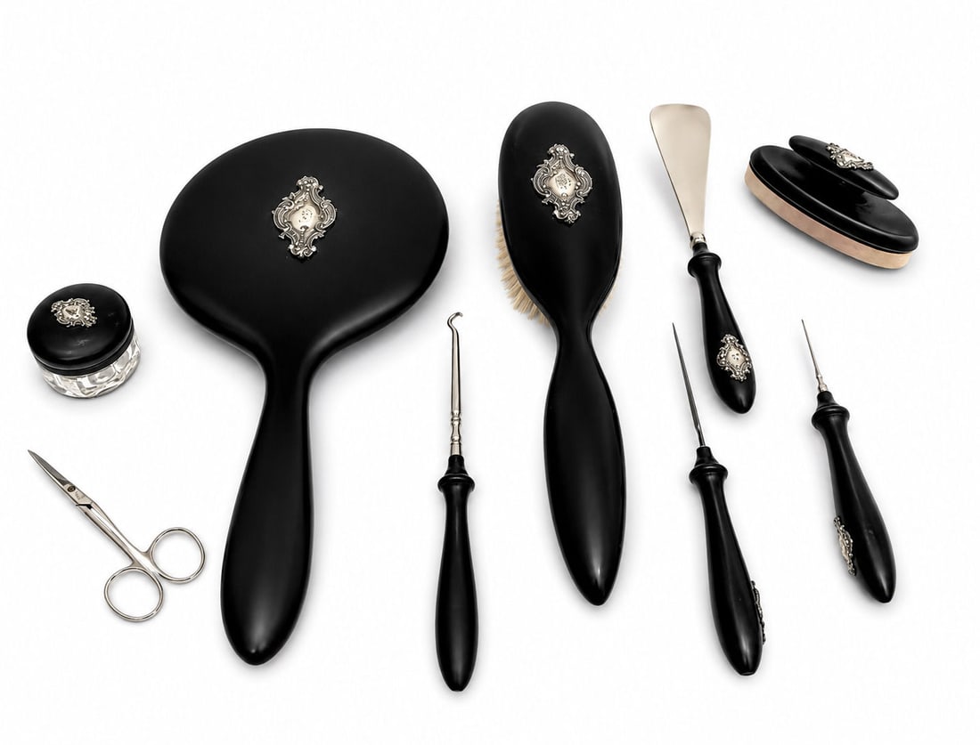 Antique English Silver and Ebony Vanity Set 9 Pieces: Refined 9-piece English vanity set featuring silver-mounted ebony tops, delicately engraved with floral and ribbon garland motifs in silver inlay. The set includes three hair brushes, one hand mirror,