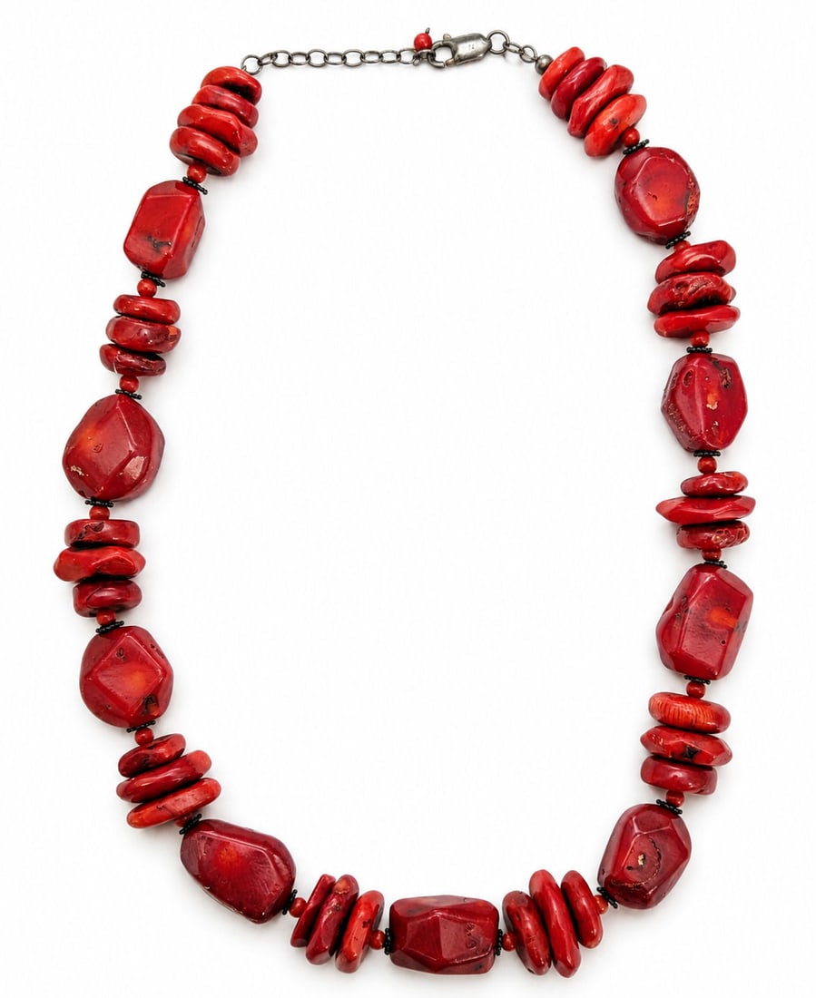Red Coral Bead Statement Necklace with Sterling Silver Clasp: This bold statement necklace features substantial, freeform natural red coral beads alternating between smooth geometric nuggets and discoid spacer beads. Small dark accent beads separate the primary 