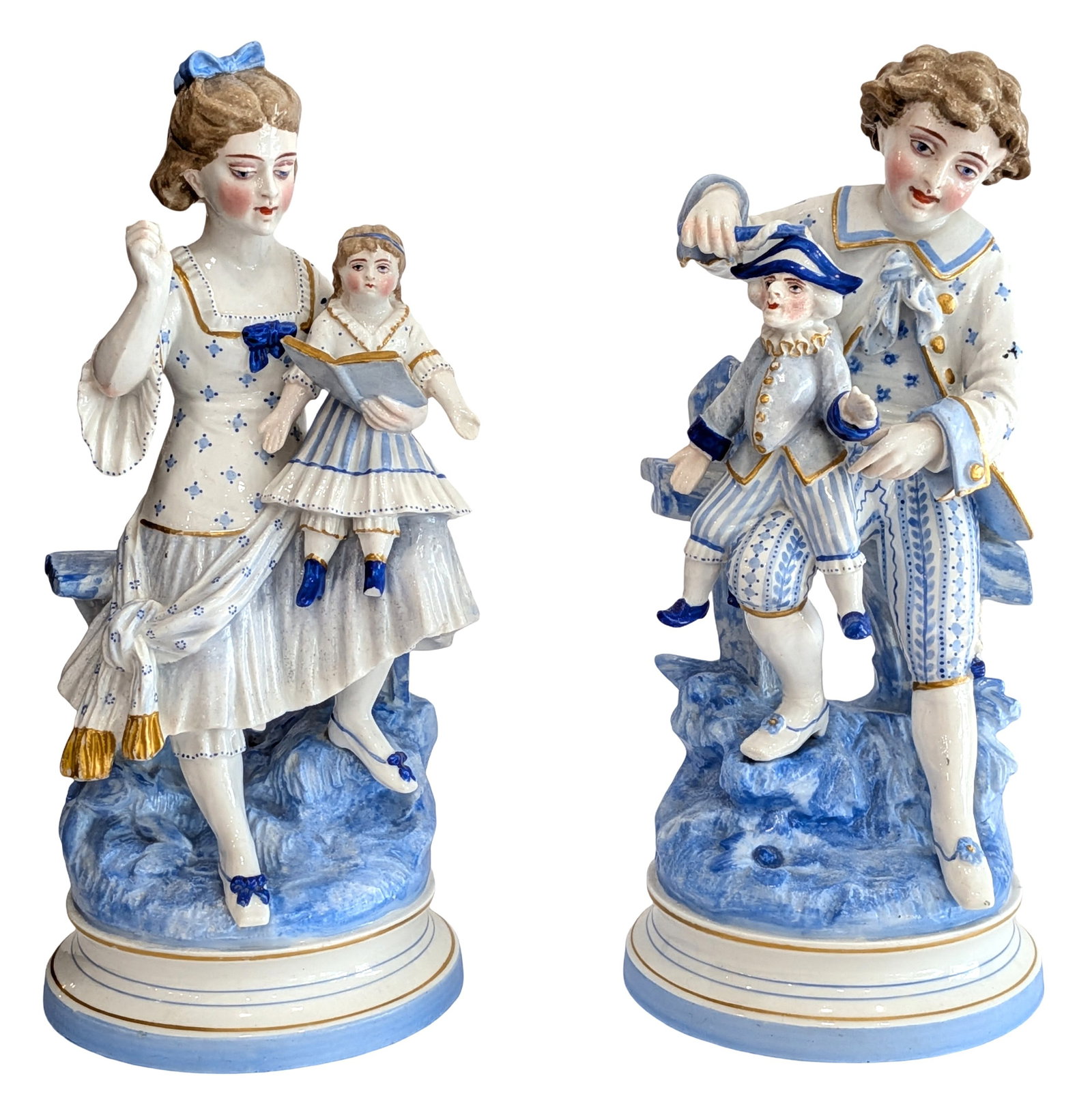 Antique Victorian Bisque Porcelain Companion Figurines of Children with Dolls Blue & White Pair: Charming antique porcelain companion figurines depicting two Victorian-era children seated on rustic garden benches, each interacting with a doll. One figure portrays a young girl holding a doll and a