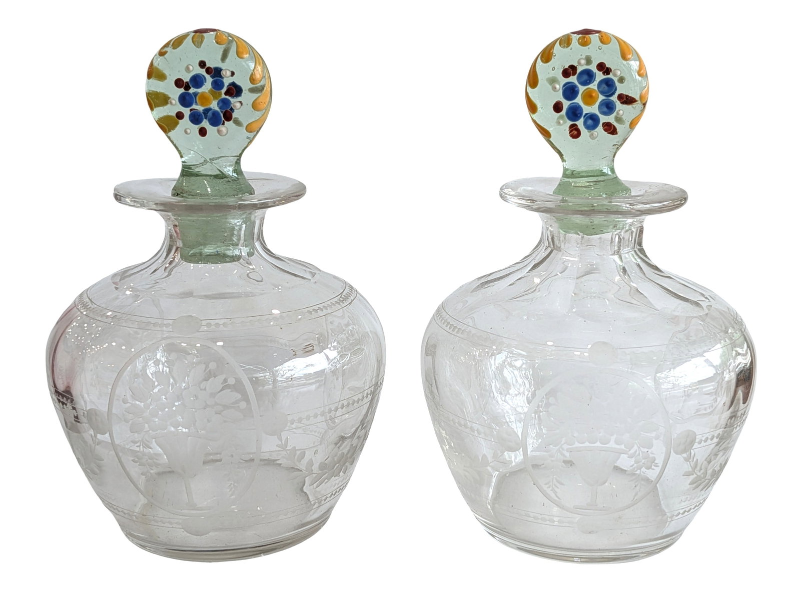 Pair of Engraved Glass Decanters with Applied Venetian-Style Millefiori Stoppers: Charming pair of hand-blown clear glass decanters featuring finely engraved floral and foliate decoration. Each globular-form decanter is decorated with frosted wheel-engraved flower basket medallions