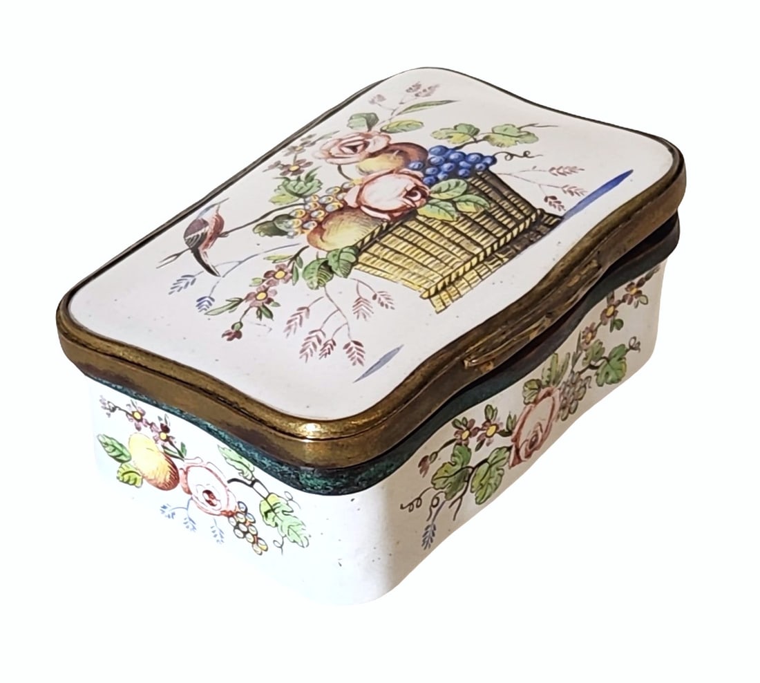 Enamel Snuff Box with Floral and Fruit Basket Motif, Possibly 19th Century: Charming rectangular enamel snuff box, possibly 19th century, featuring a hand-painted central motif of a woven basket overflowing with fruit and flowers, accompanied by a perched bird. The sides are 