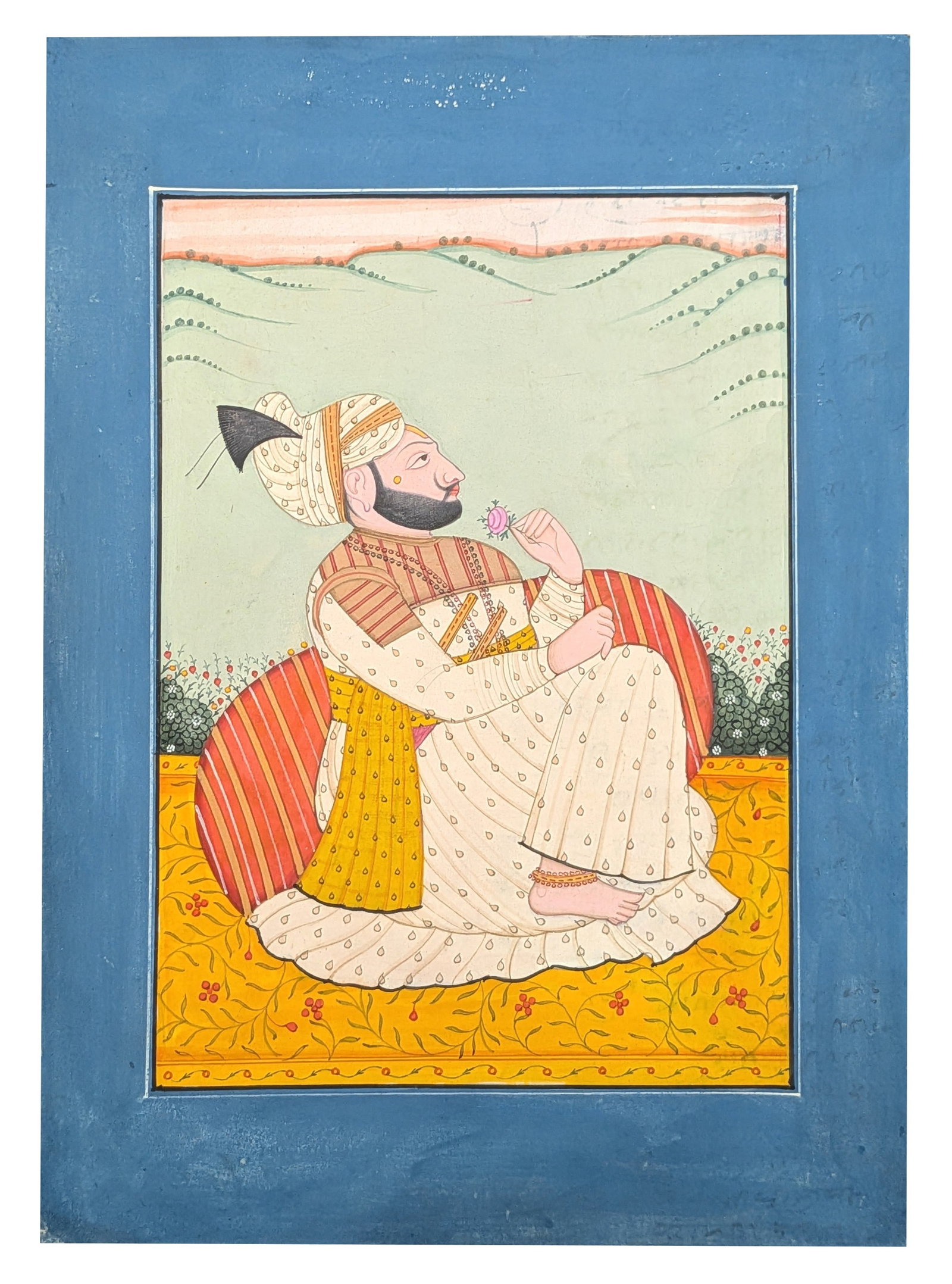 Indian Miniature Painting of a Nobleman Holding a Flower: Indian miniature painting depicting a finely dressed nobleman seated on a richly patterned yellow terrace cushion while holding a pink blossom in contemplation. He wears an elegant white jama decorate