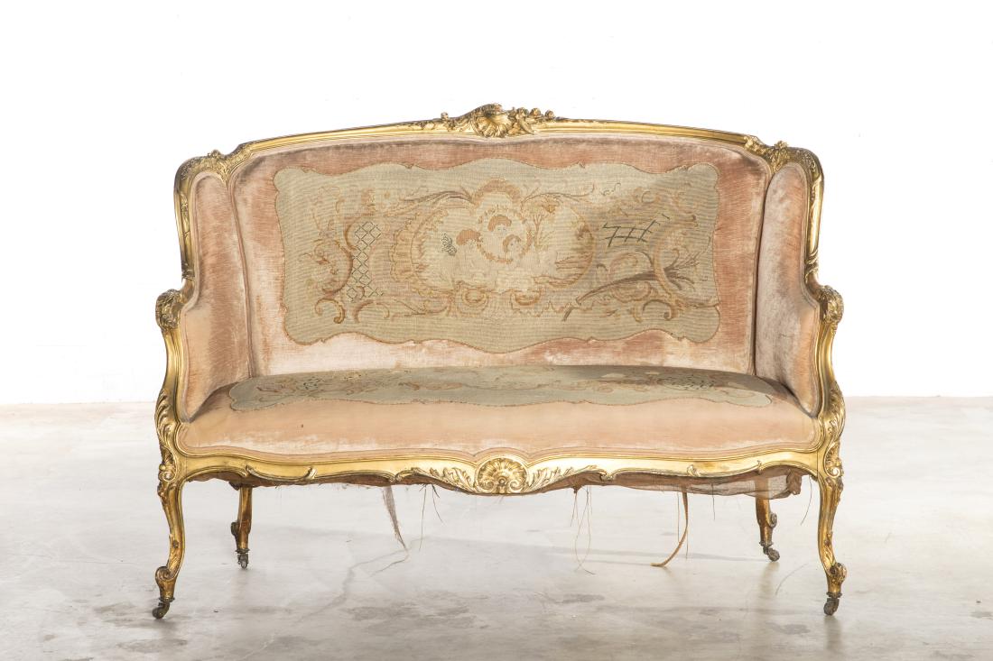 A Louis XV style carved giltwood canape: A Louis XV style carved giltwood canapÃ© late 19th century The carved scroll feet raised on brass casters. height 41in (104cm); width 57in (145cm); depth of seat 20 1/2in (52cm)